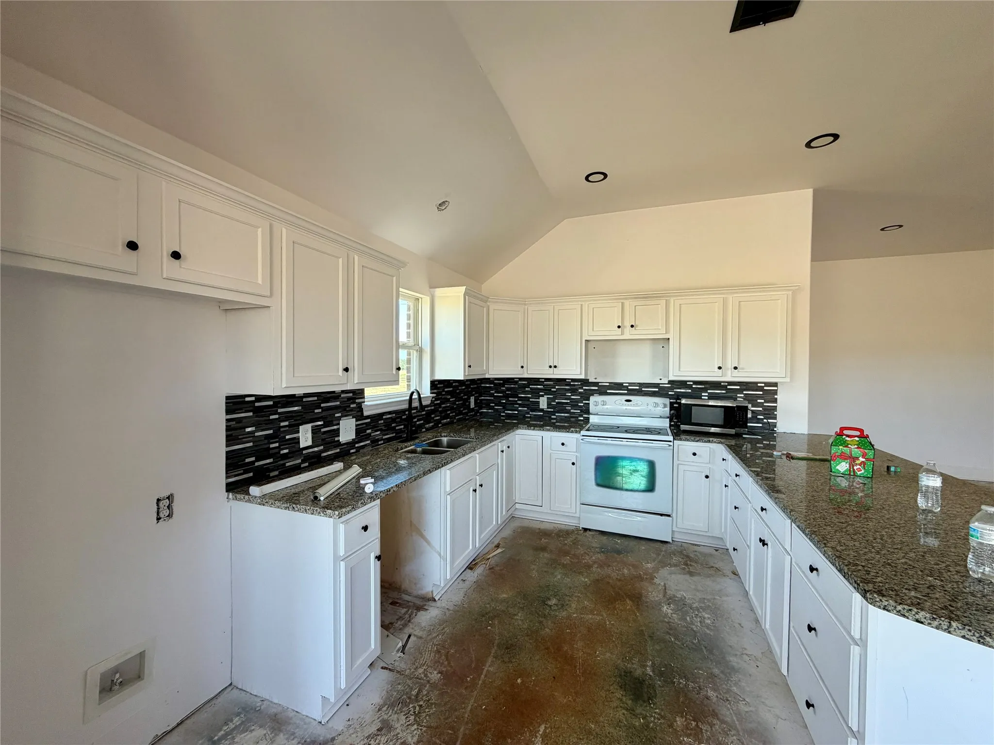 Spacious kitchen featuring white cabinetry, granite countertops, a mosaic tile backsplash, and recessed lighting