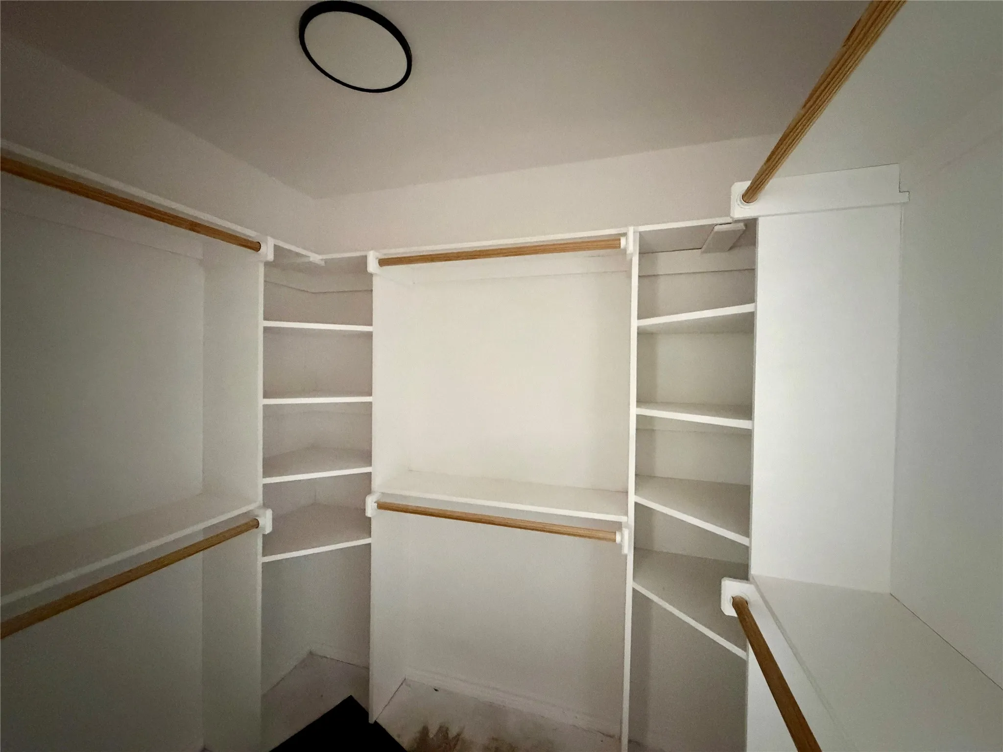 Spacious closet featuring multiple wood-finish hanging rods and extensive shelving