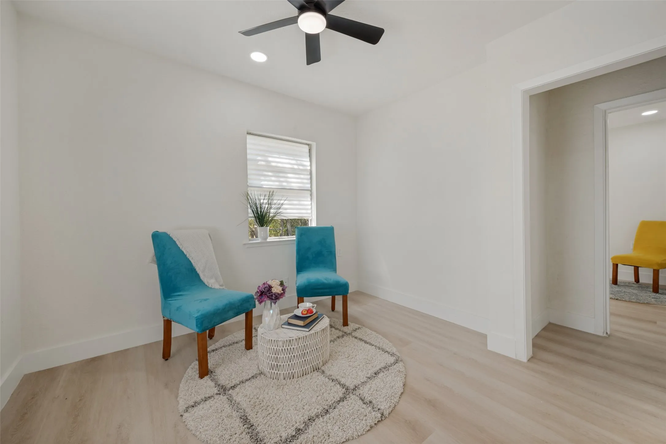 Light wood-finish flooring with white baseboards, recessed lighting, and a ceiling fan