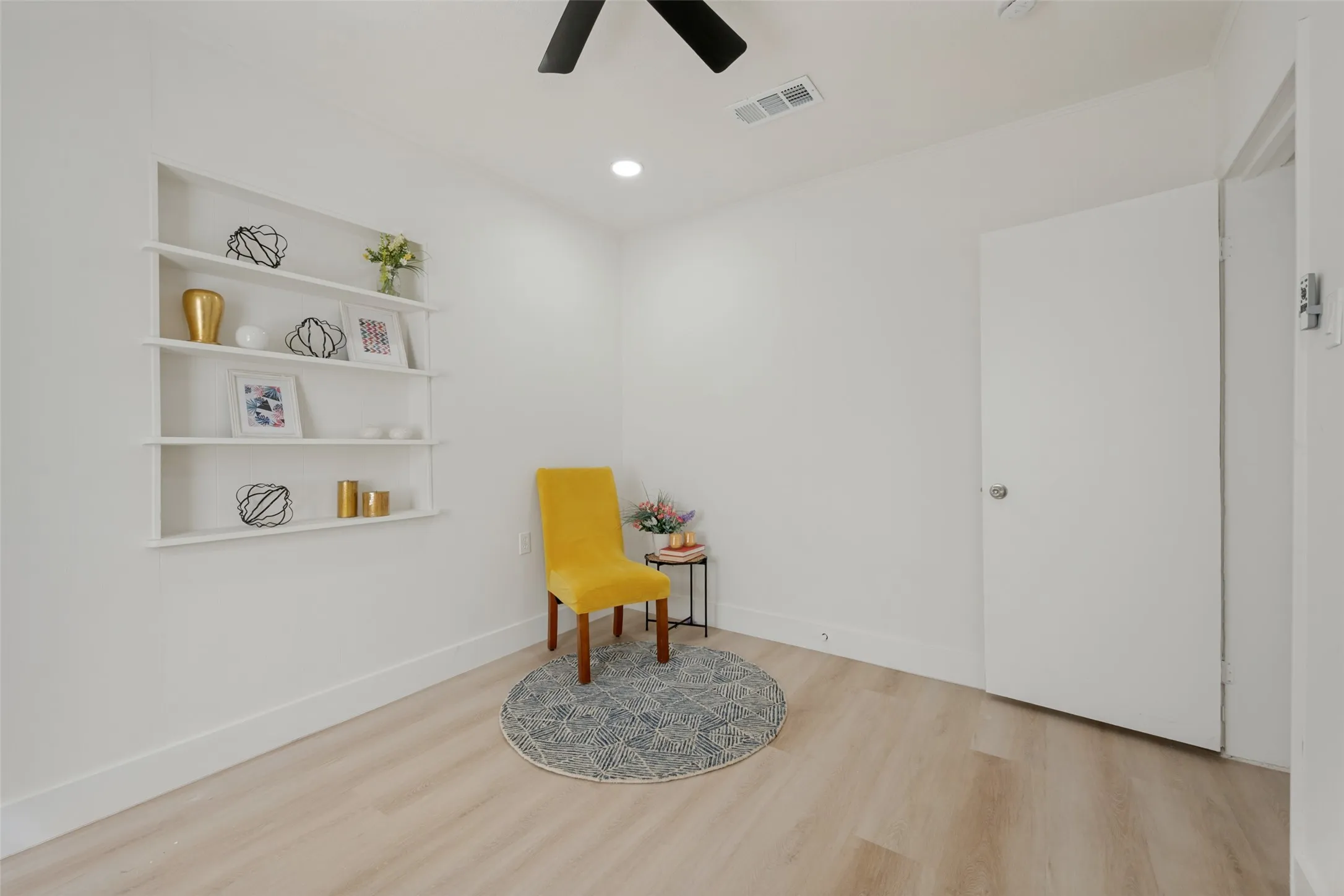 Recessed wall shelving, light wood-finish flooring, ceiling fan, recessed lighting, and a white interior door