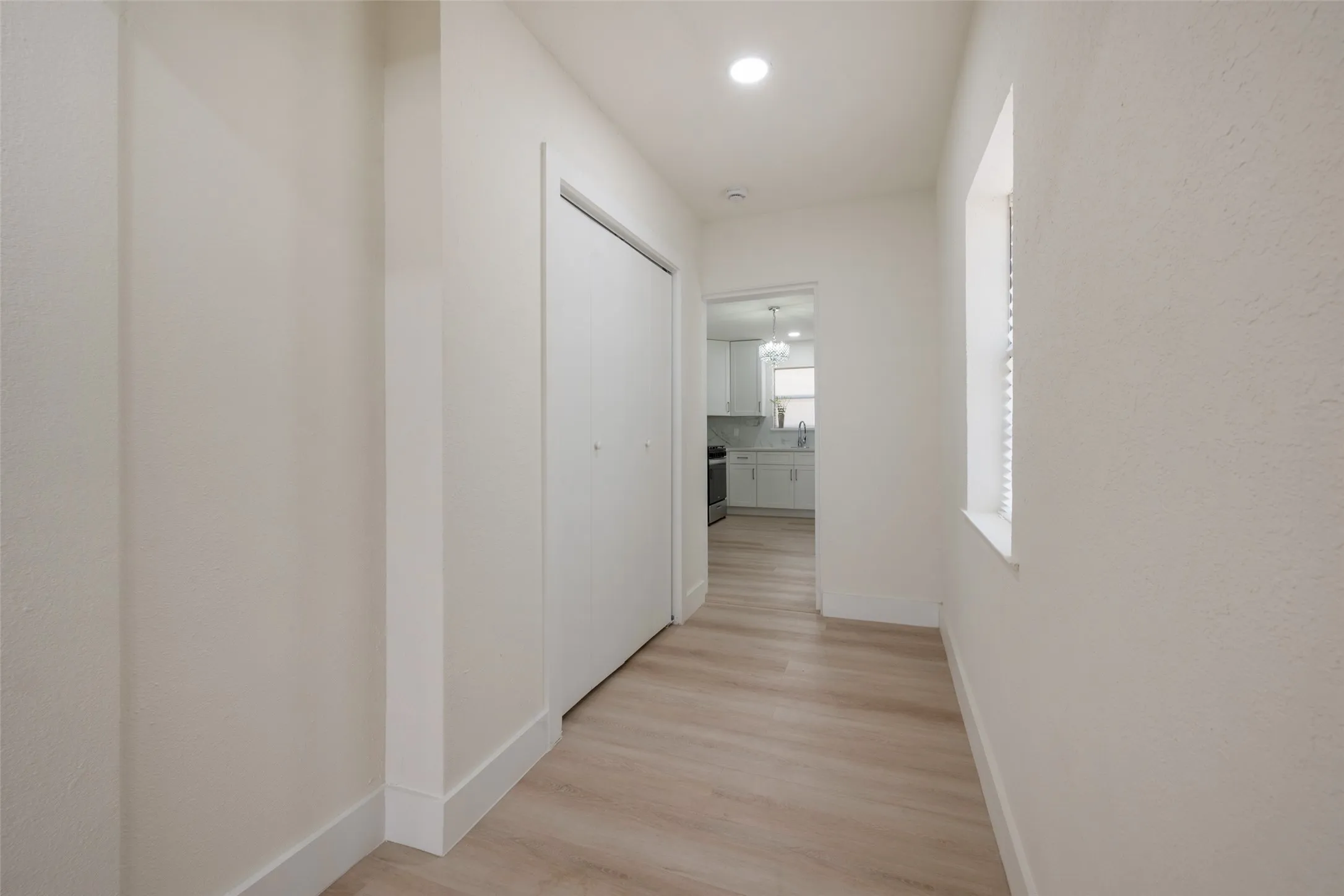 Recessed lighting, wood-finish flooring, and white bi-fold closet doors