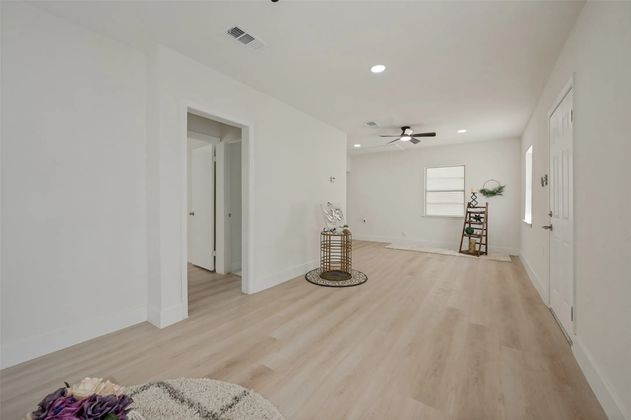Open-concept living space with light wood-finish flooring, recessed lighting, and a ceiling fan