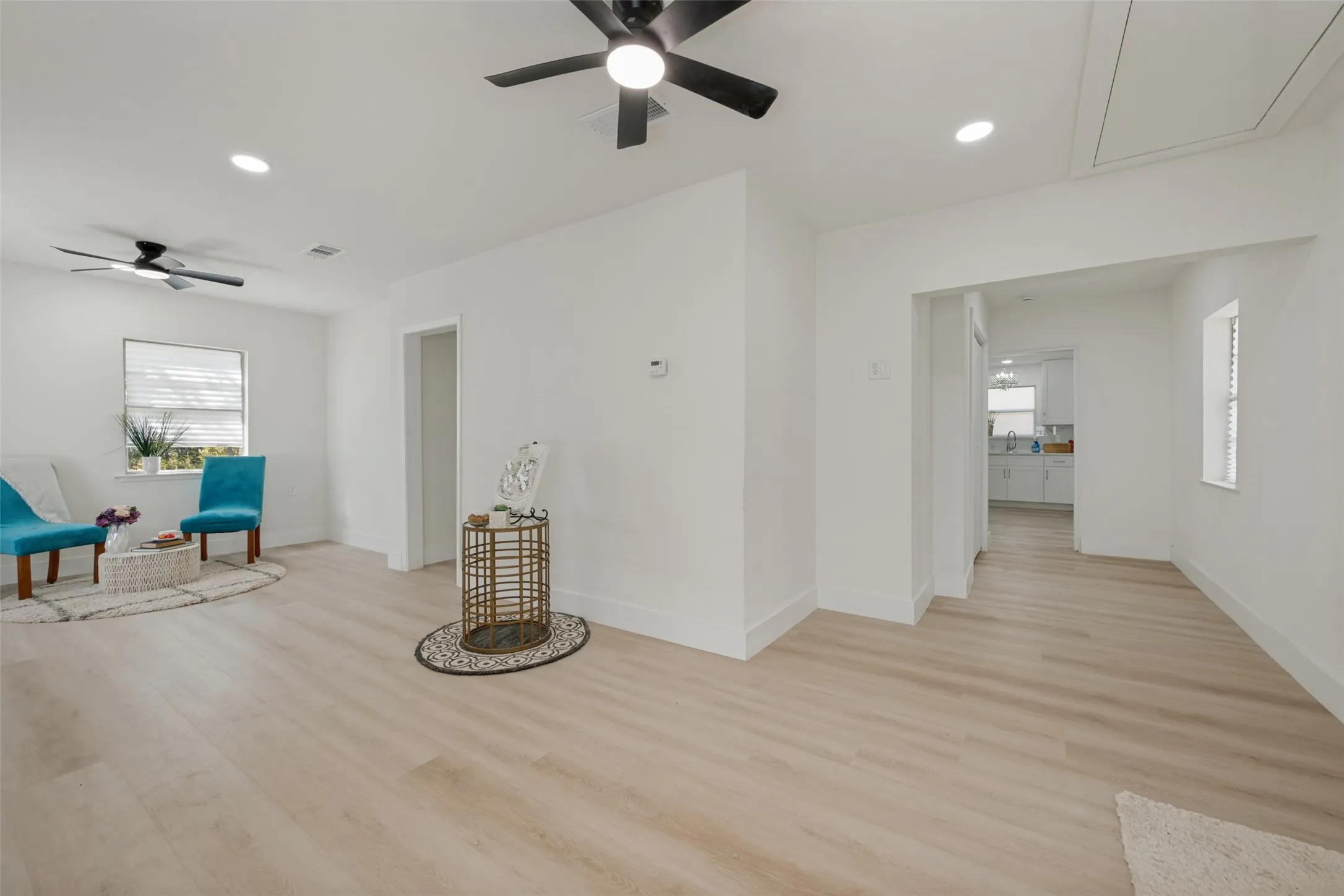 Recessed lighting, light wood-finish flooring, two ceiling fans, white walls, and a window with blinds