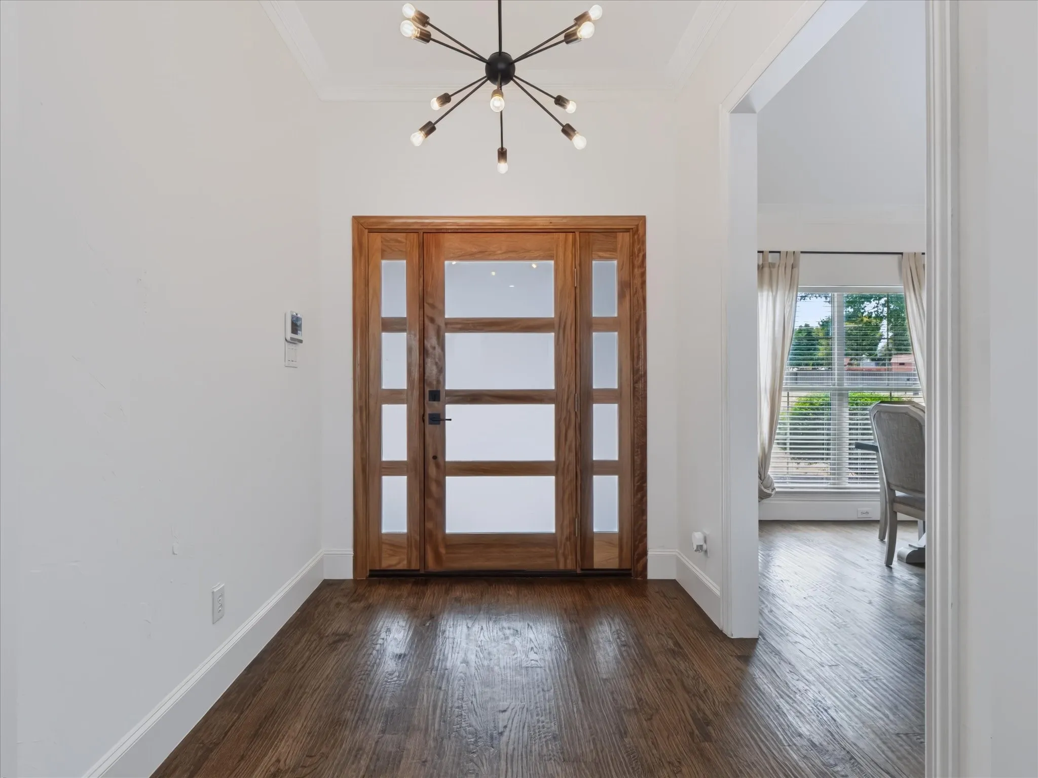 Wood-finish flooring throughout, bright white walls, and a multi-panel wood entry door with frosted glass accents