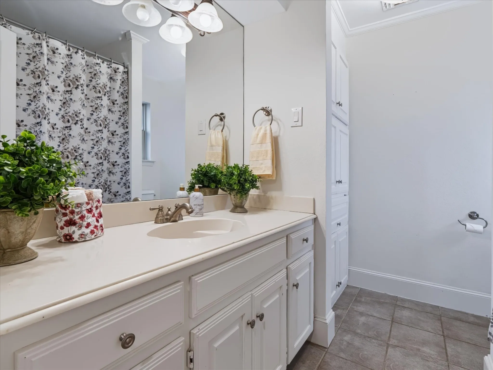 Built-in vanity with single basin, white cabinetry, integrated mirror, wall-mounted light fixture, and tiled flooring