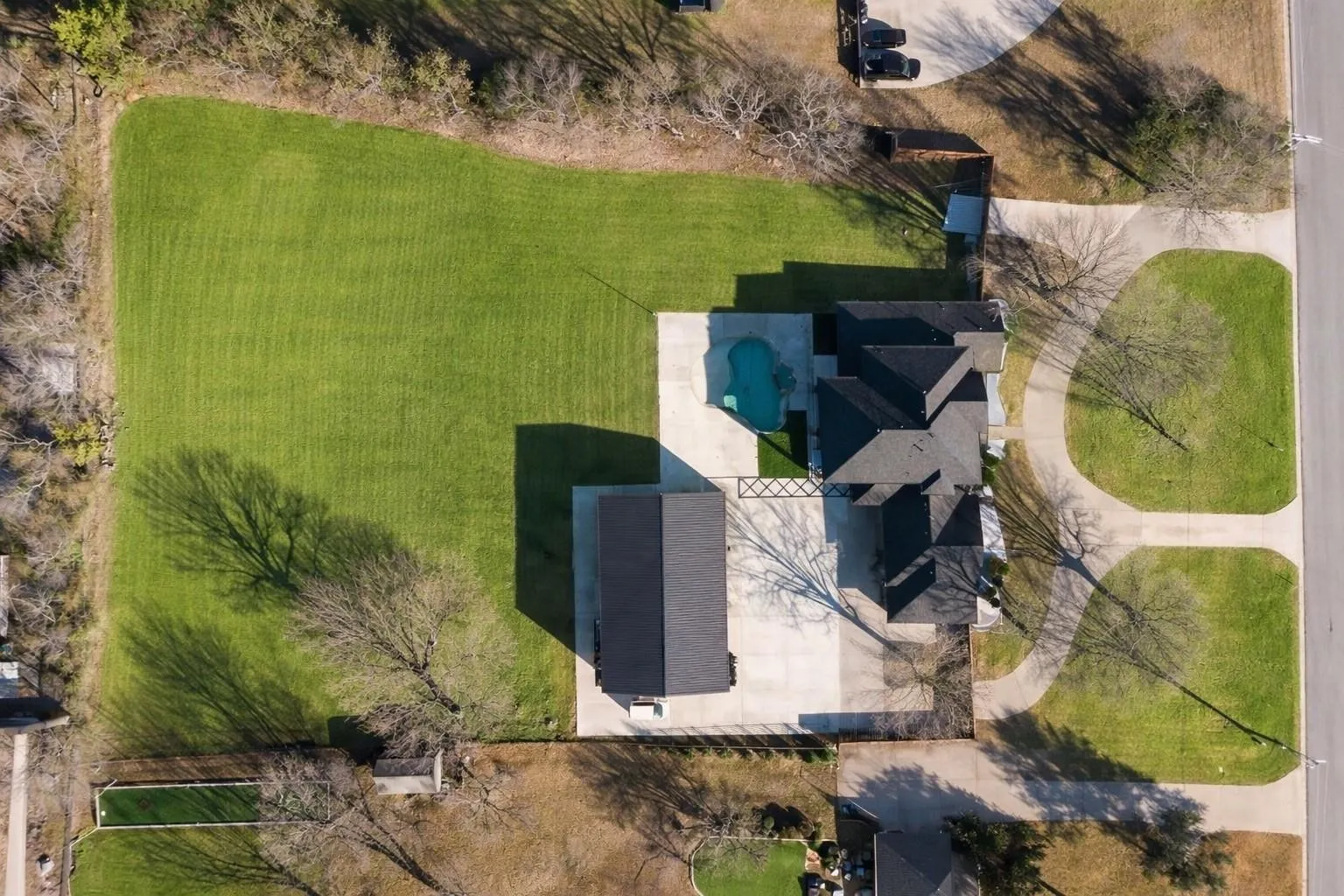 Expansive property featuring a large manicured lawn, a detached structure, an in-ground pool, and a paved driveway