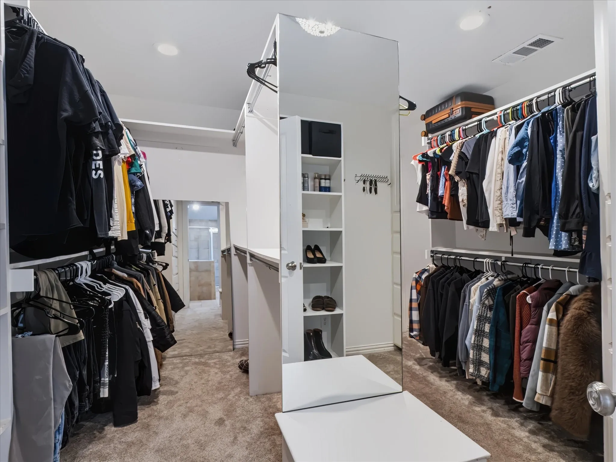 Carpeted walk-in closet featuring extensive hanging storage, built-in shelving, a full-length mirror, and recessed lighting