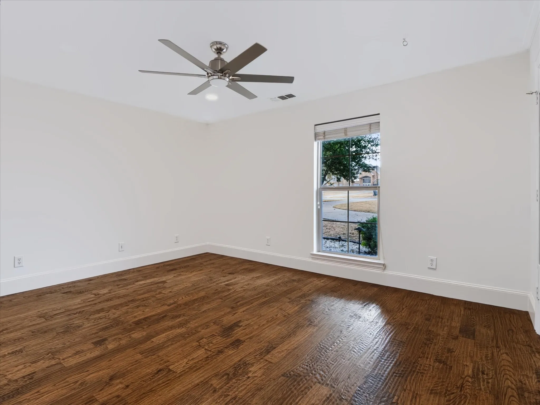 Wood-finish flooring, single window, contemporary ceiling fan, white walls, and bright overhead lighting