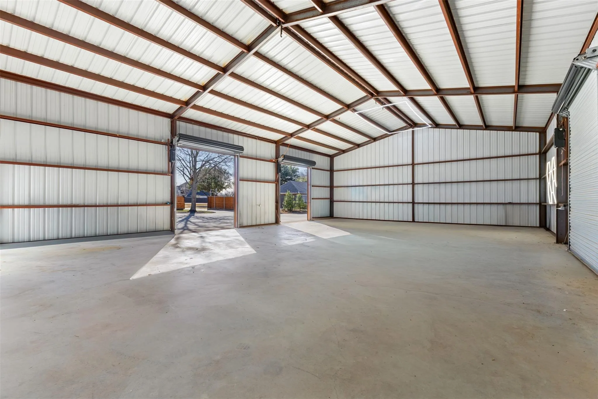Expansive interior with a concrete floor, corrugated metal walls, and a visible structural framework