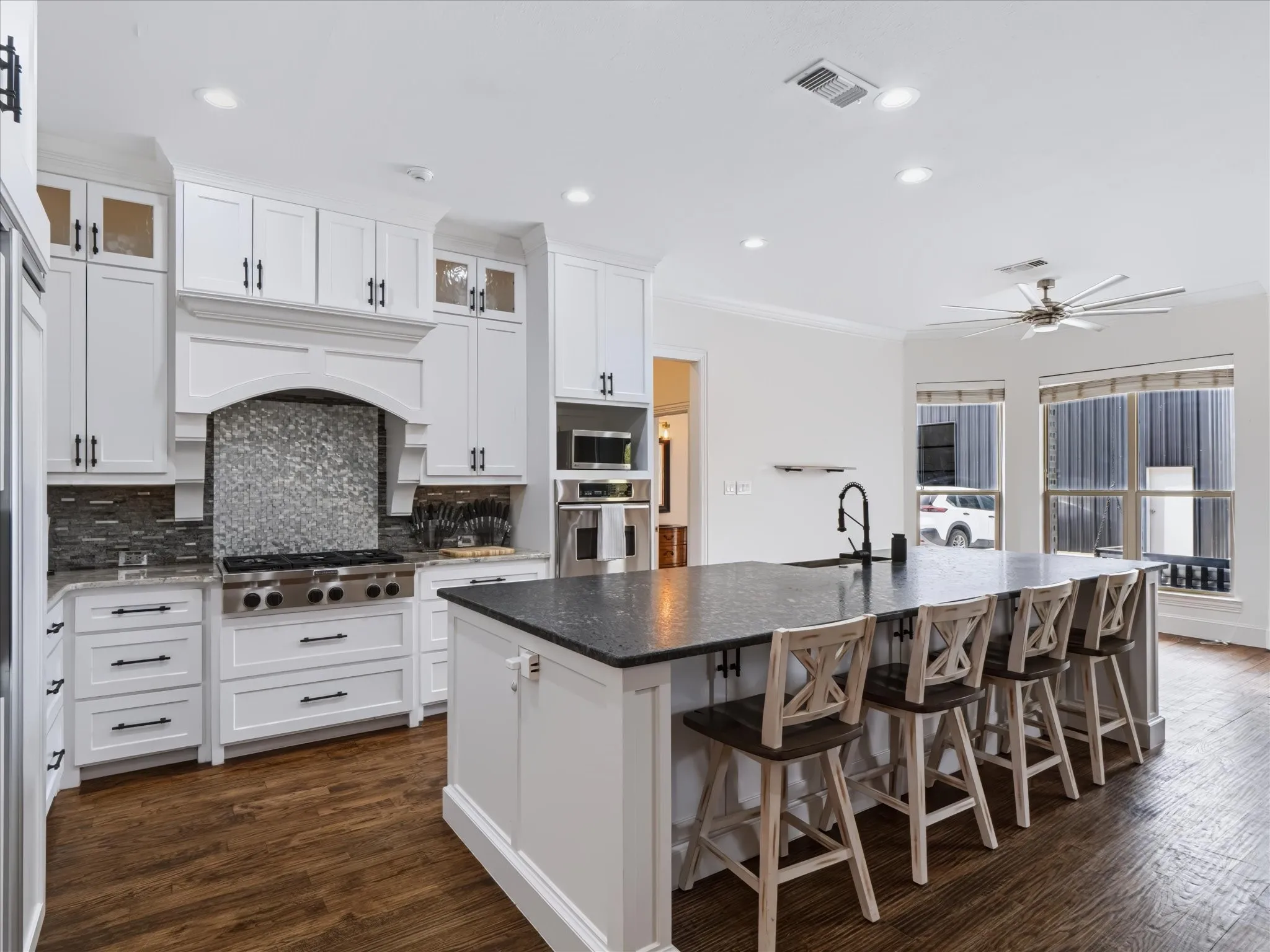 Gourmet kitchen featuring white cabinetry, stone countertops, stainless steel appliances, a multi-burner range, and wood-finish flooring