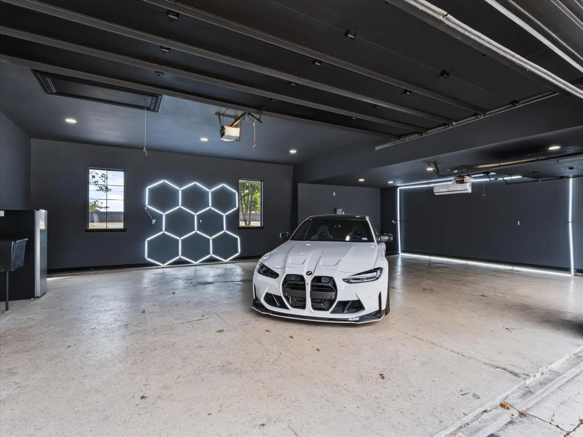 Spacious garage with exposed beam ceiling, recessed lighting, and wall-mounted hexagonal lighting feature