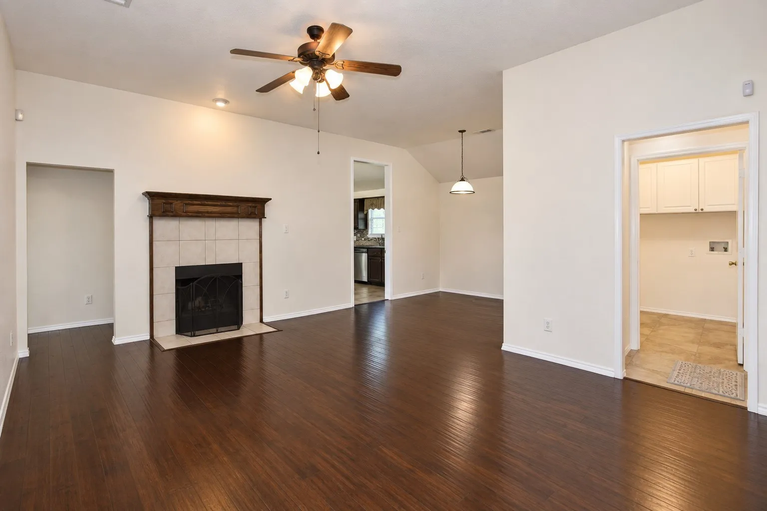 Spacious interior featuring wood-finish flooring, a tile-surround fireplace with a wood mantle, and a ceiling fan