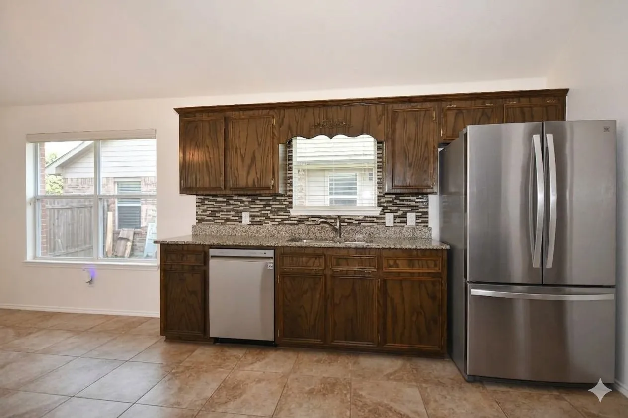 Tiled flooring, wood cabinetry, stainless steel dishwasher, stainless steel refrigerator, and mosaic tile backsplash