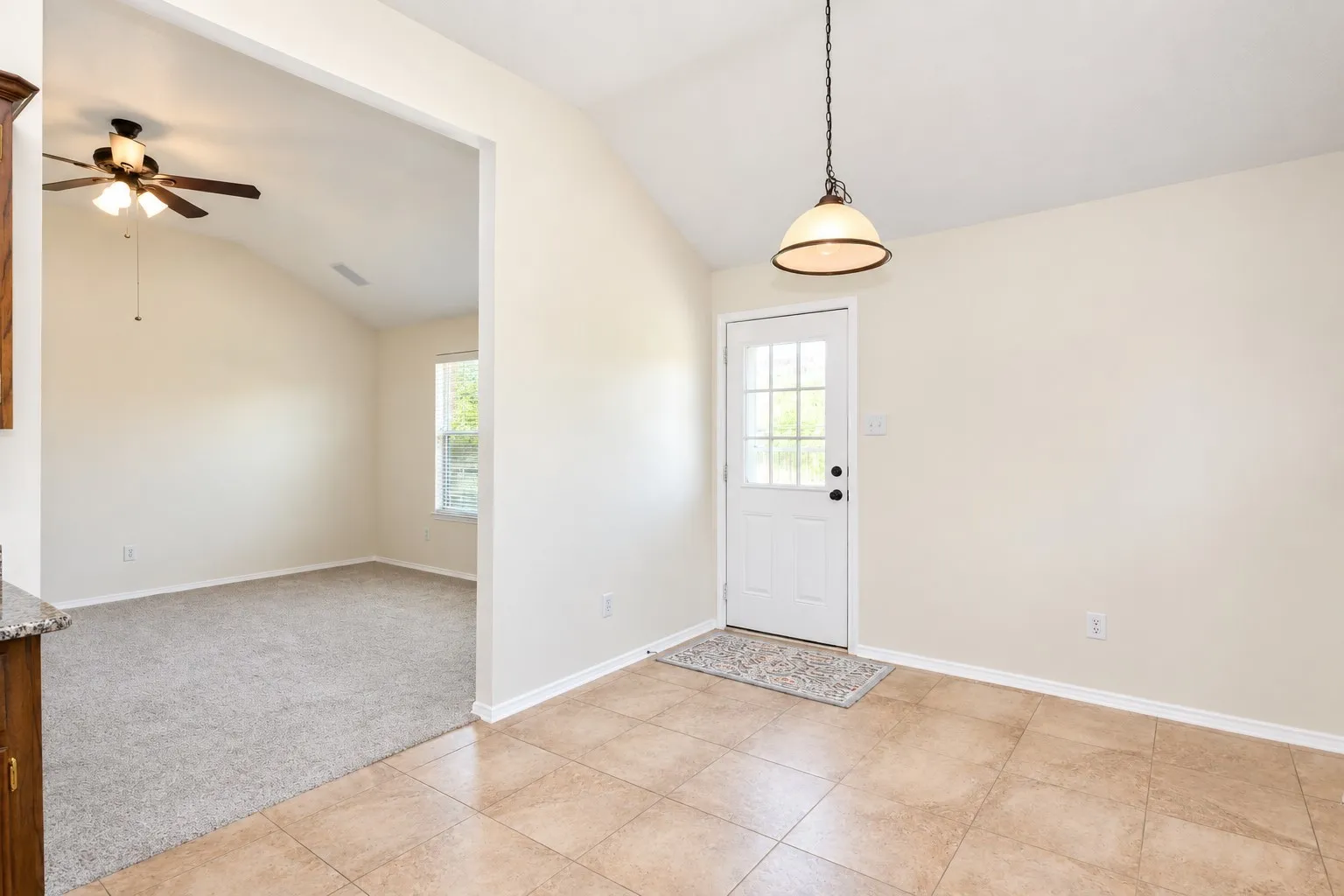Vaulted ceiling, ceiling fan, transom window, paneled door with grid glass, and tile flooring