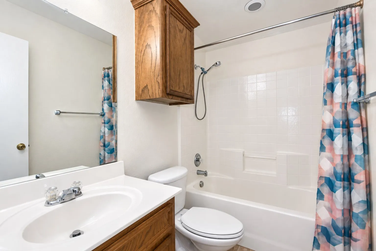 White vanity with integrated sink, chrome faucet, wood-finish cabinetry, and a full-width mirror