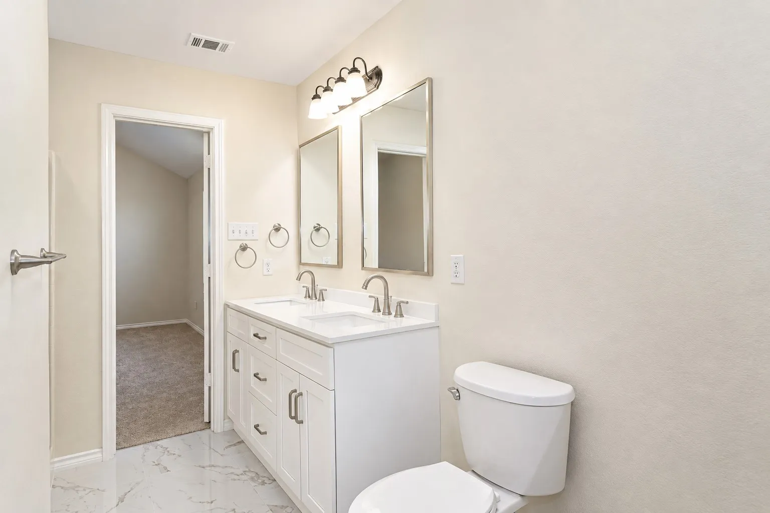 Dual vanity with white cabinetry, brushed nickel hardware, and white countertops
