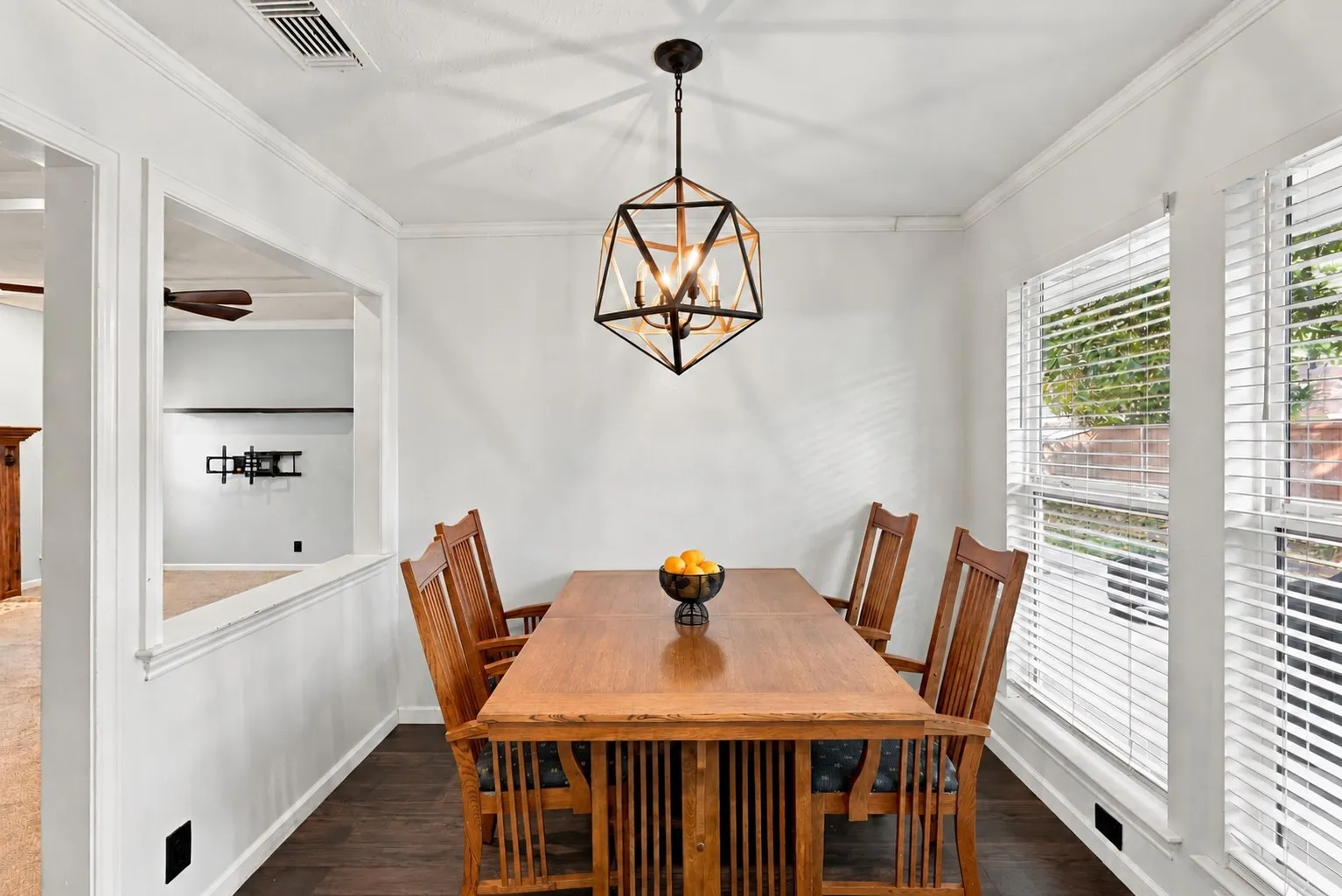 Wood-finish flooring, contemporary geometric chandelier, white trim details, and bright windows with blinds
