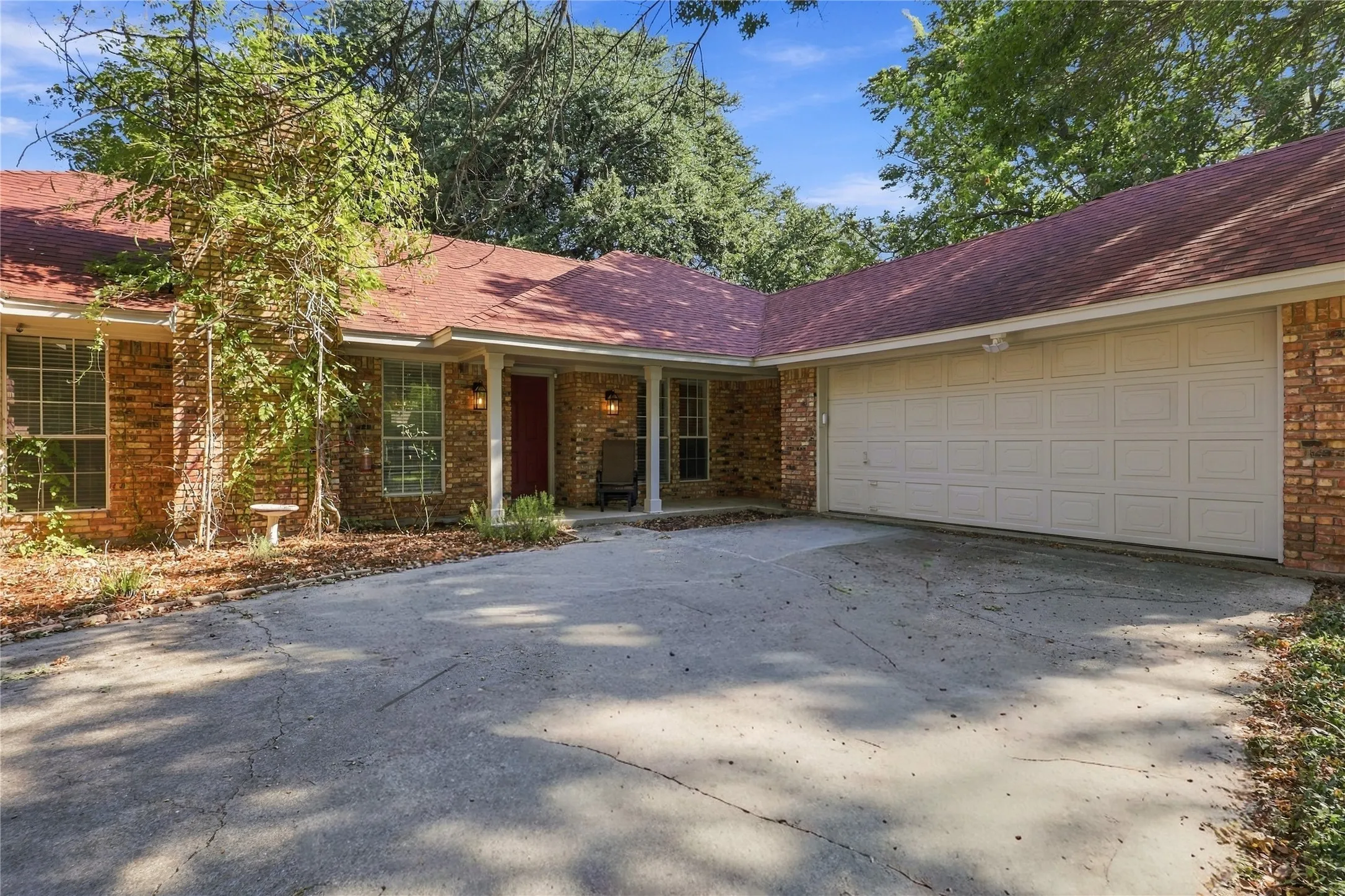 Brick exterior with a covered entry, attached garage, and a concrete driveway