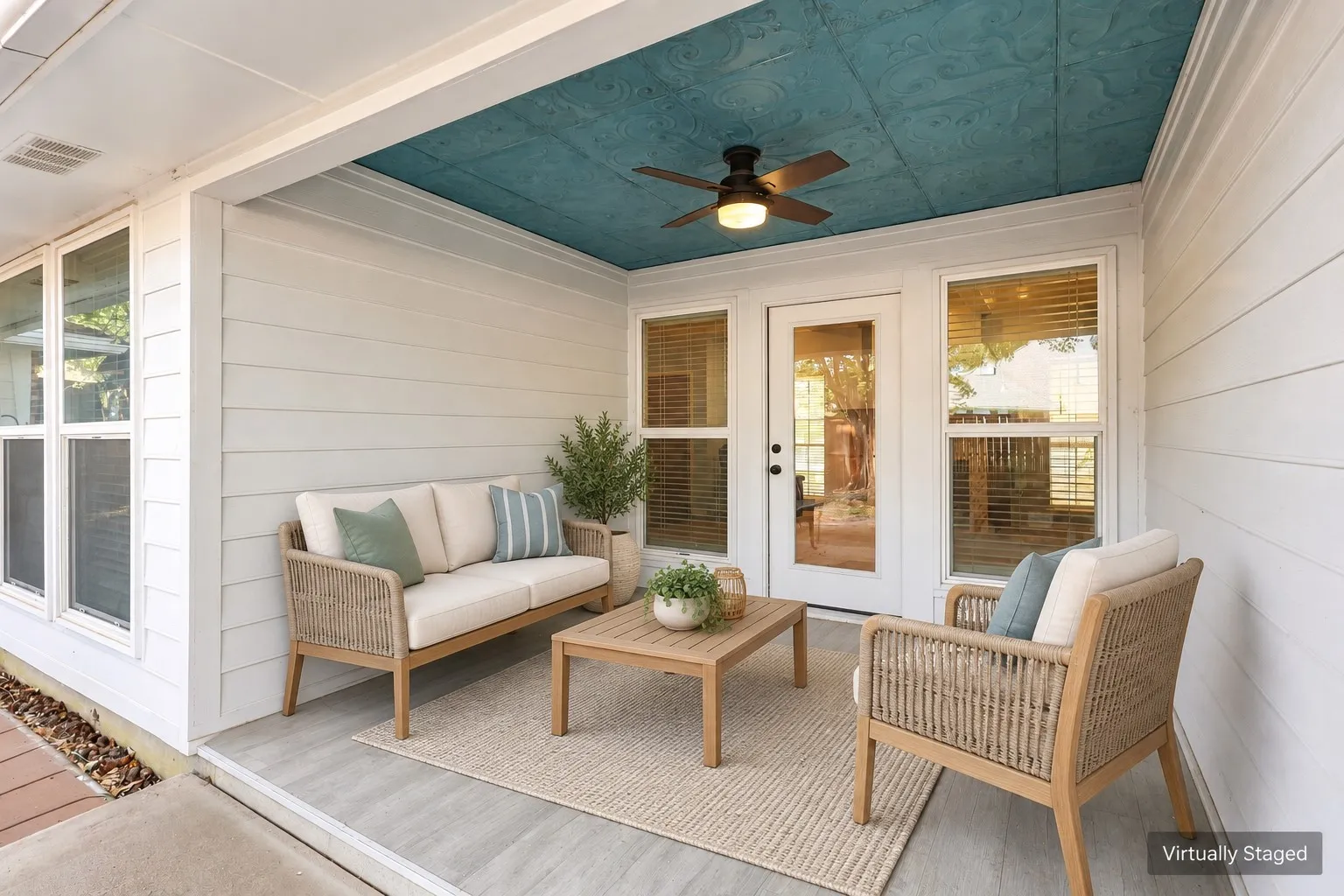 Covered outdoor patio with a textured teal ceiling, ceiling fan, and wood-finish flooring