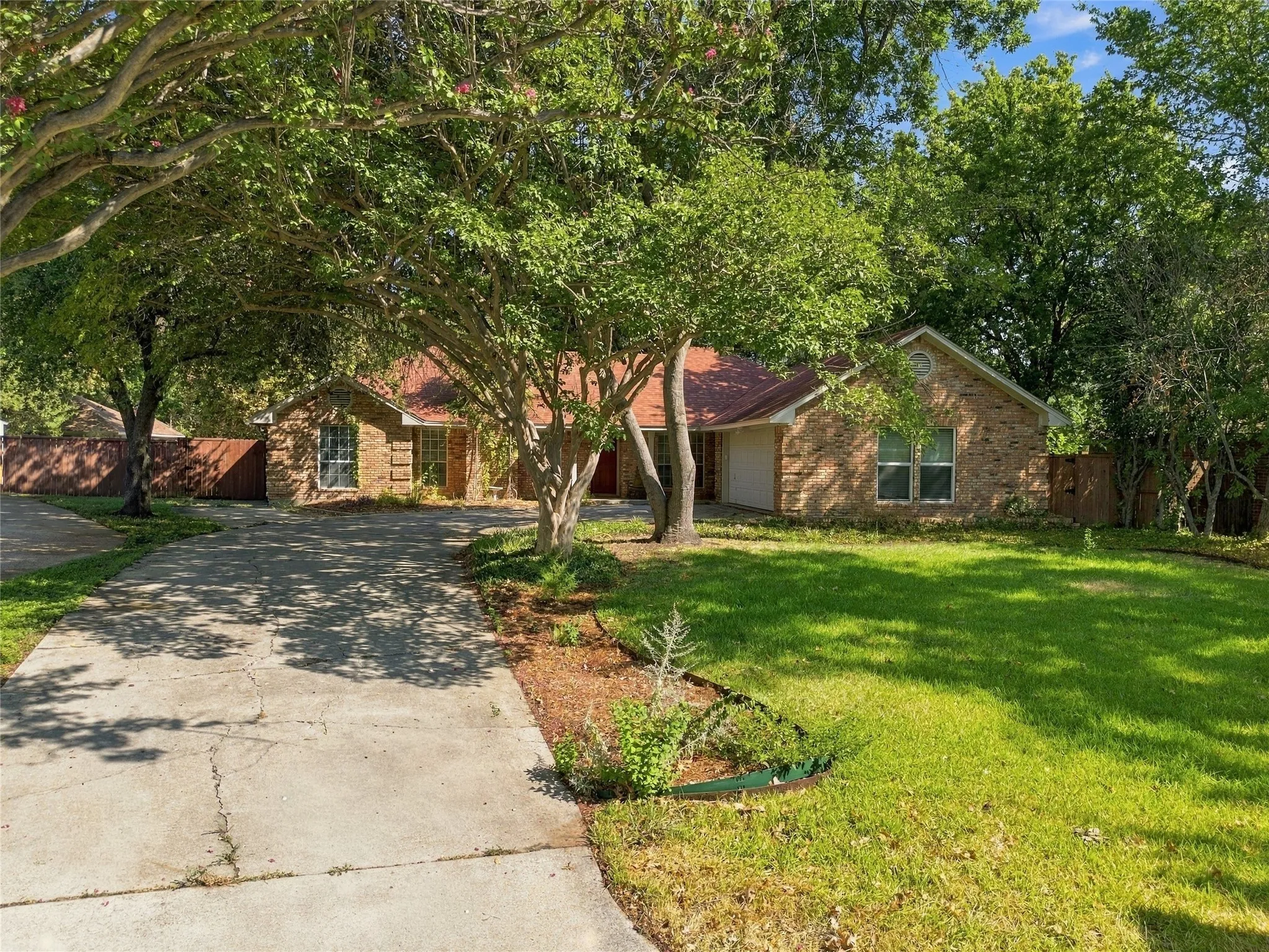Brick exterior with a covered entry, mature trees, and an expansive front lawn