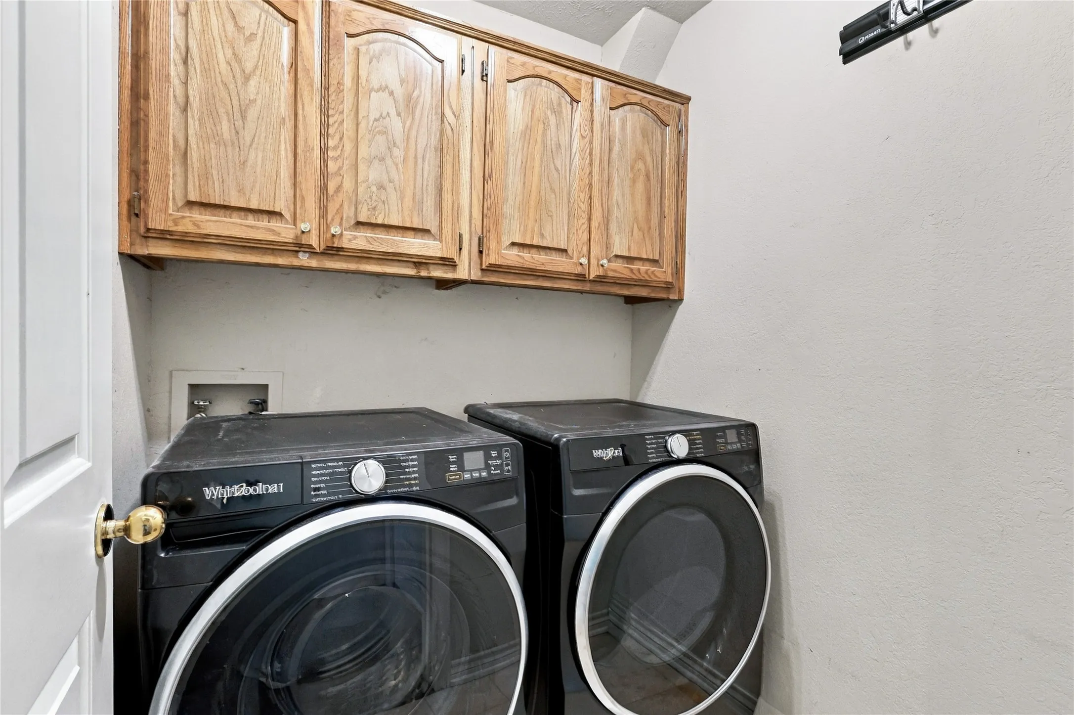 Overhead wood cabinetry provides storage within this utility space