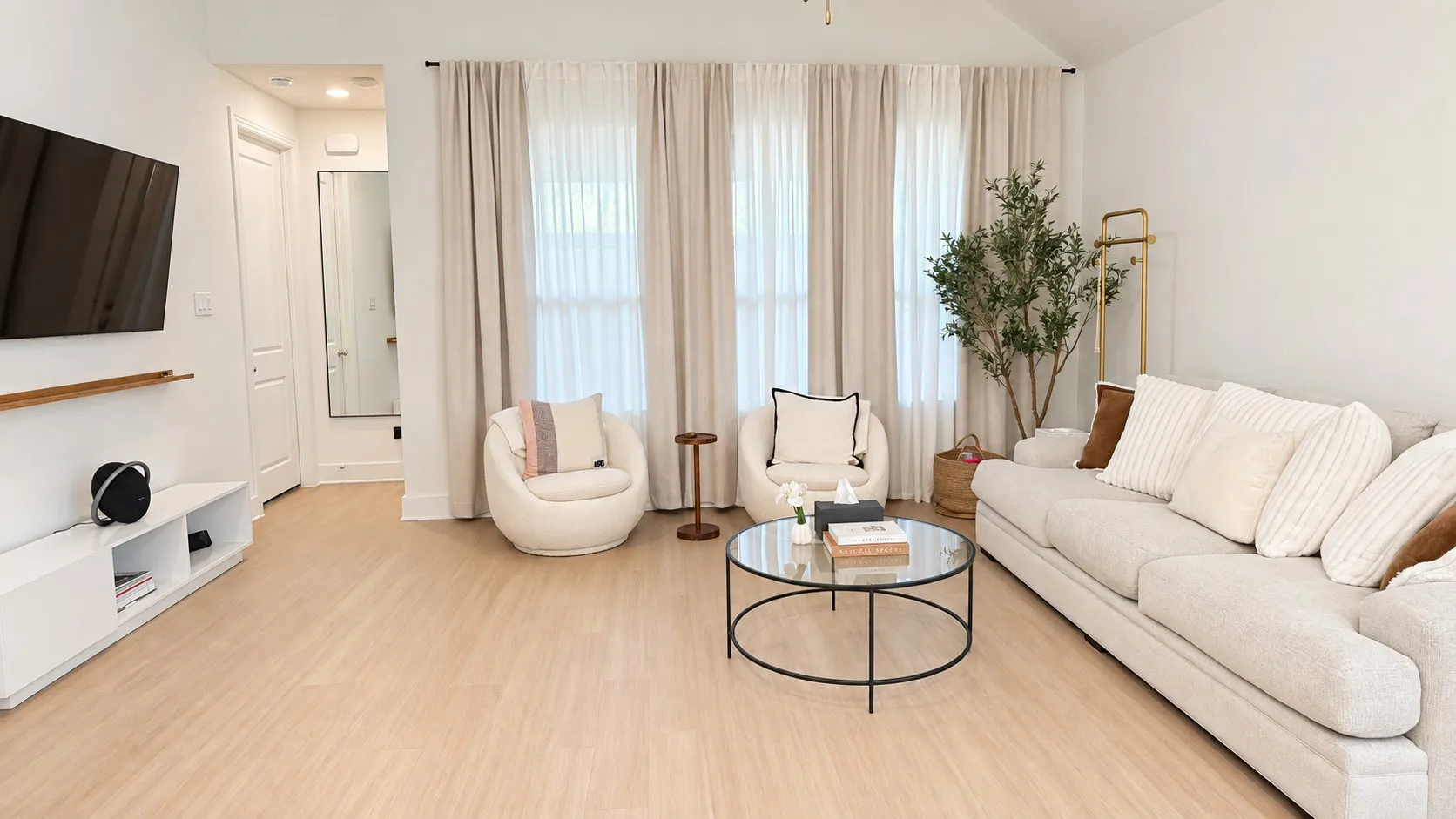 Light wood-finish flooring, vaulted ceiling, and ample natural light through tall windows
