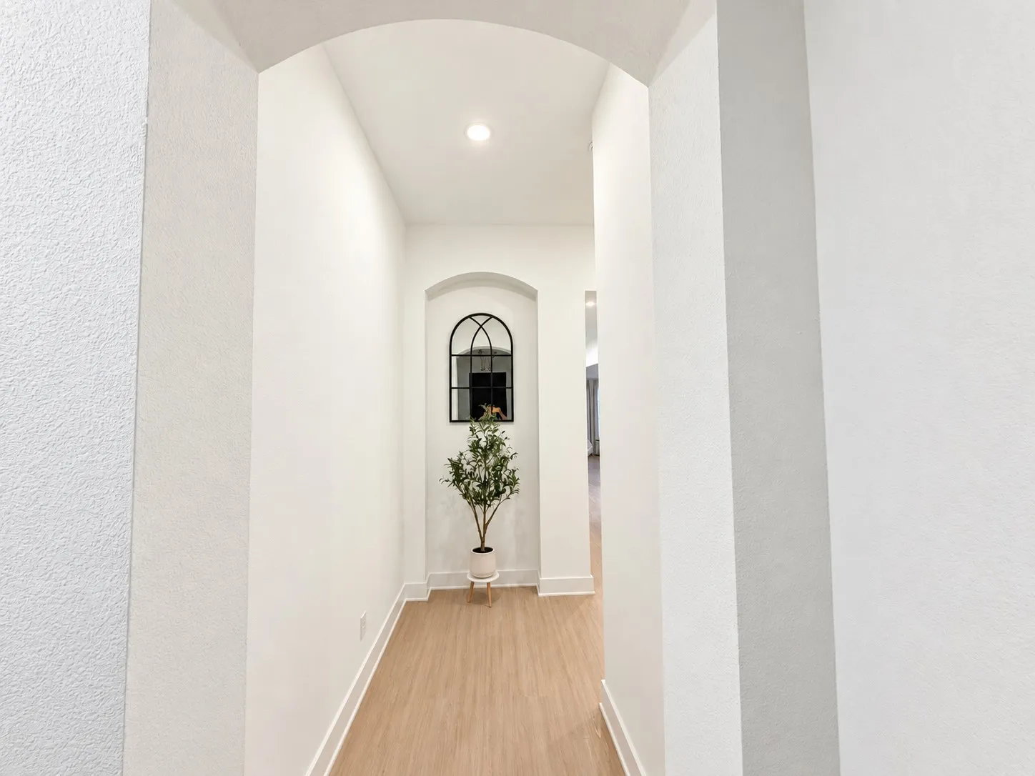 Archway entry with recessed lighting, wood-finish flooring, and white baseboards