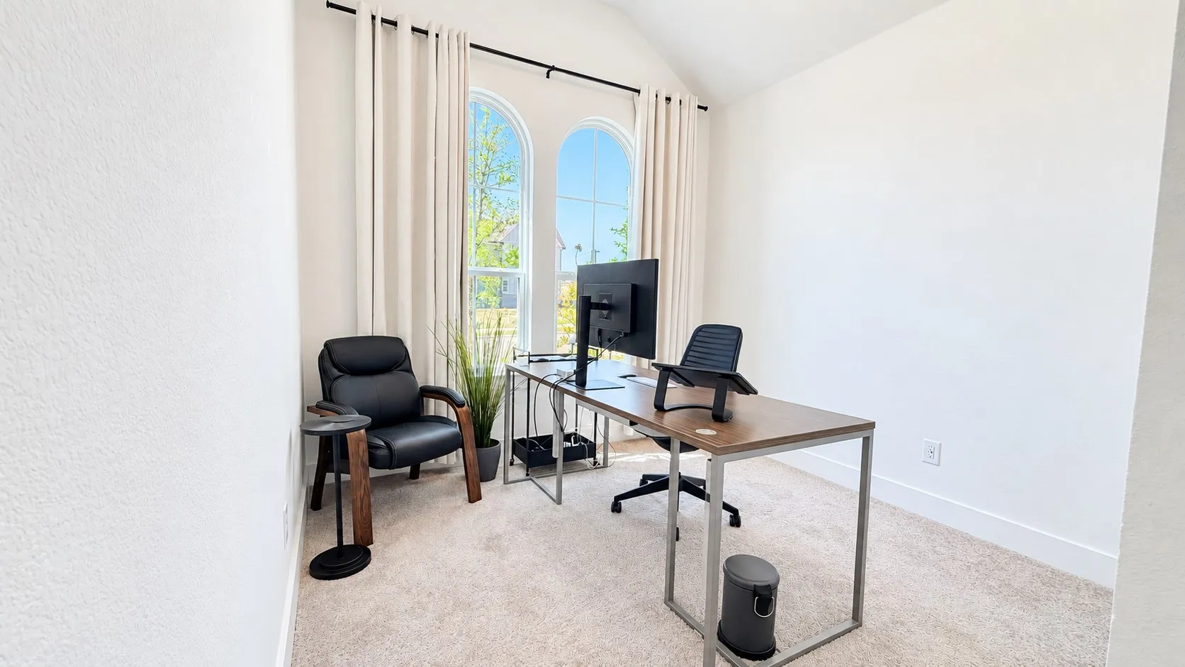 Arched windows with drapery rods, light-toned walls, and neutral carpeting
