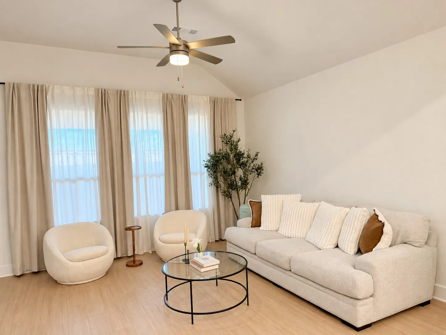 Vaulted ceiling, wood-finish flooring, ceiling fan with integrated lighting, expansive wall space, and multiple windows