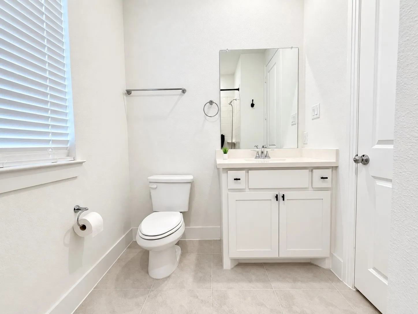 White vanity with a single basin, light-colored countertop, and dark hardware