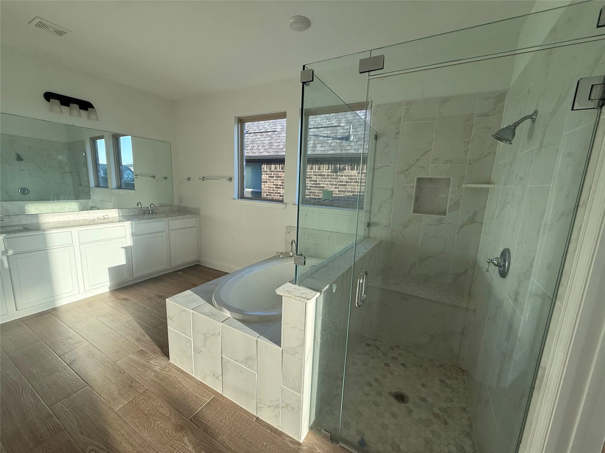 Glass-enclosed shower with tile surround and built-in bench