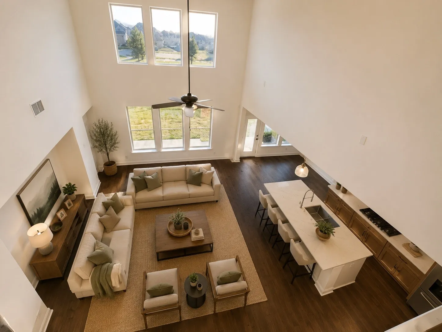 Soaring ceilings with upper-level windows, wood-finish flooring, and a kitchen island with seating