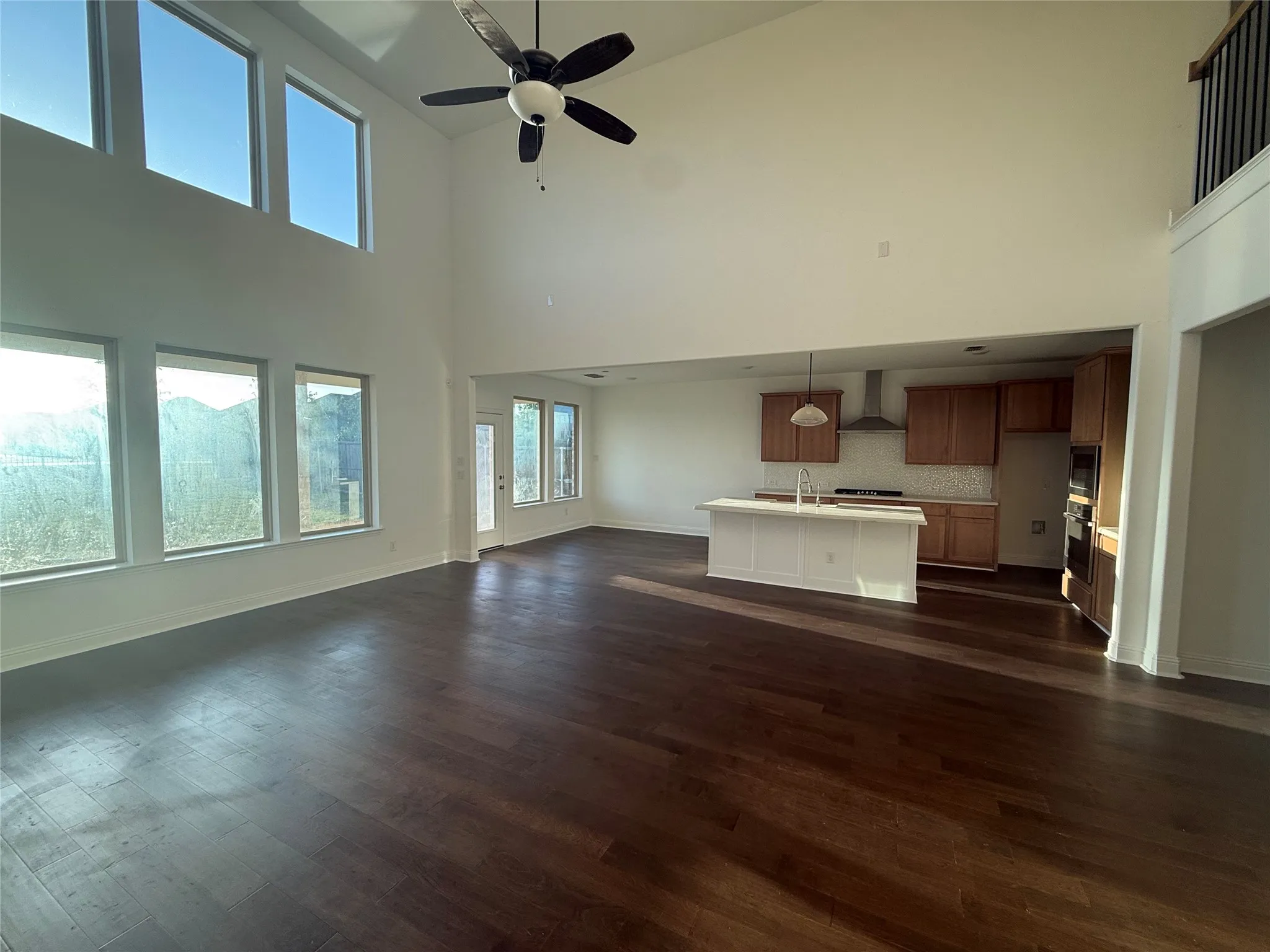 Vaulted ceilings with an attached ceiling fan, wood-finish flooring, and multiple windows