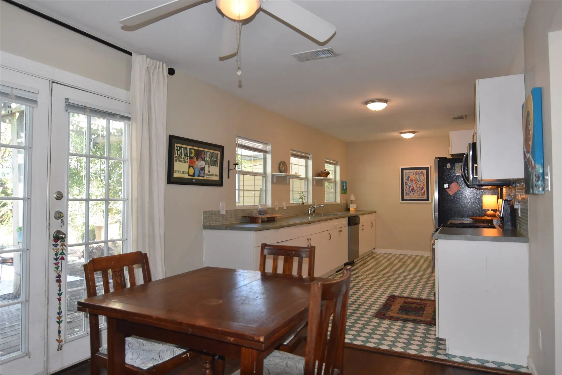 Functional kitchen with white cabinetry, stainless steel appliances, and a tiled backsplash