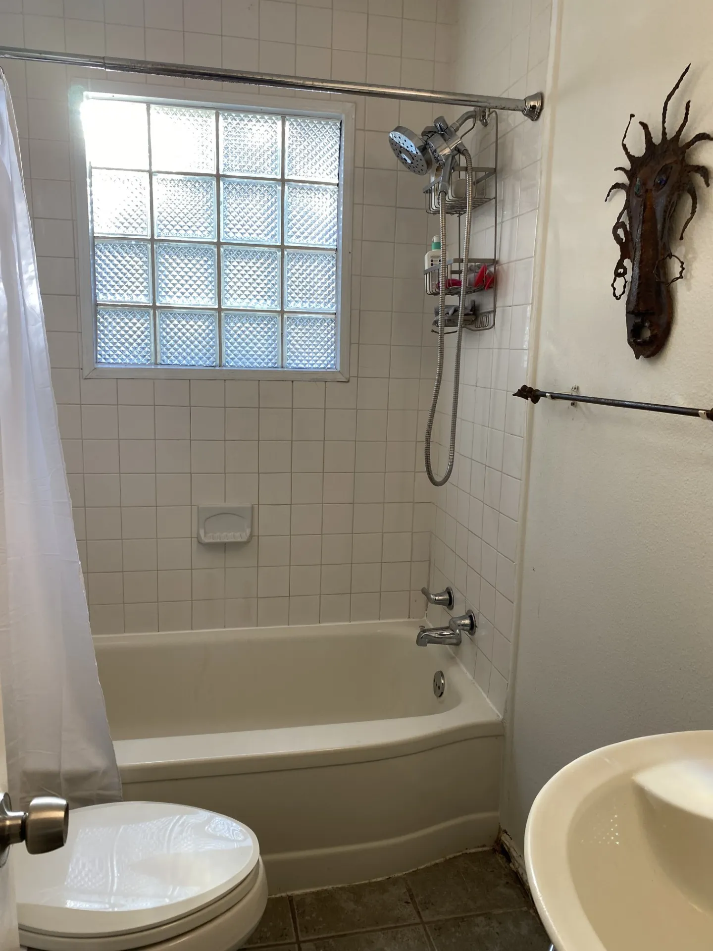Bathtub with chrome fixtures, tiled walls, and a glass block window