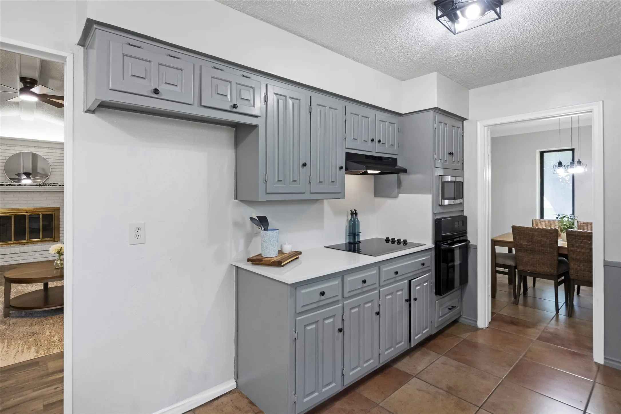 Galley kitchen with grey cabinetry, built-in microwave, wall oven, and cooktop