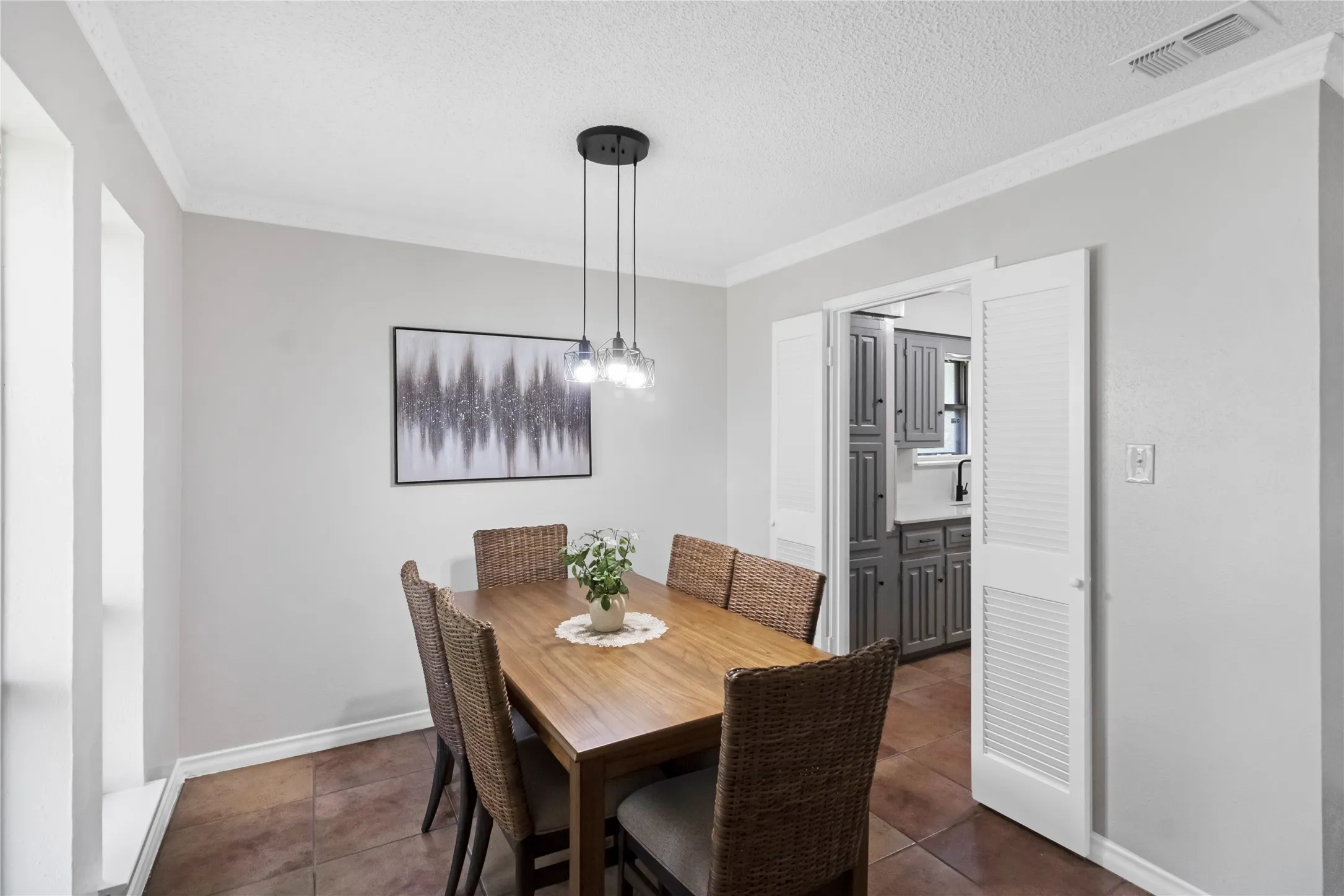 Neutral wall paint, crown molding, tile flooring, modern pendant lighting, and white louvered bifold doors