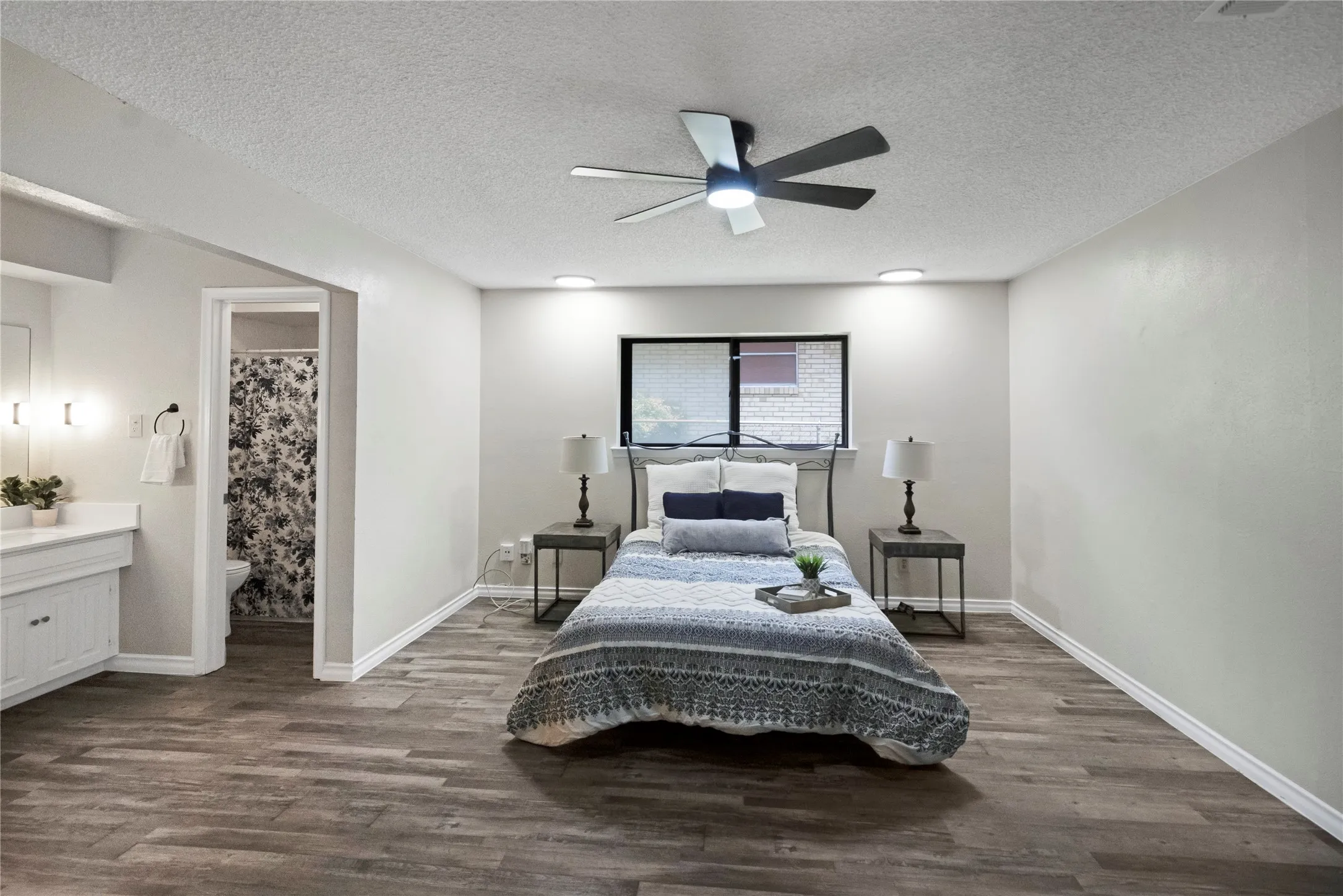 Wood-finish flooring throughout, ceiling fan with integrated lighting, recessed lighting, and an attached bathroom