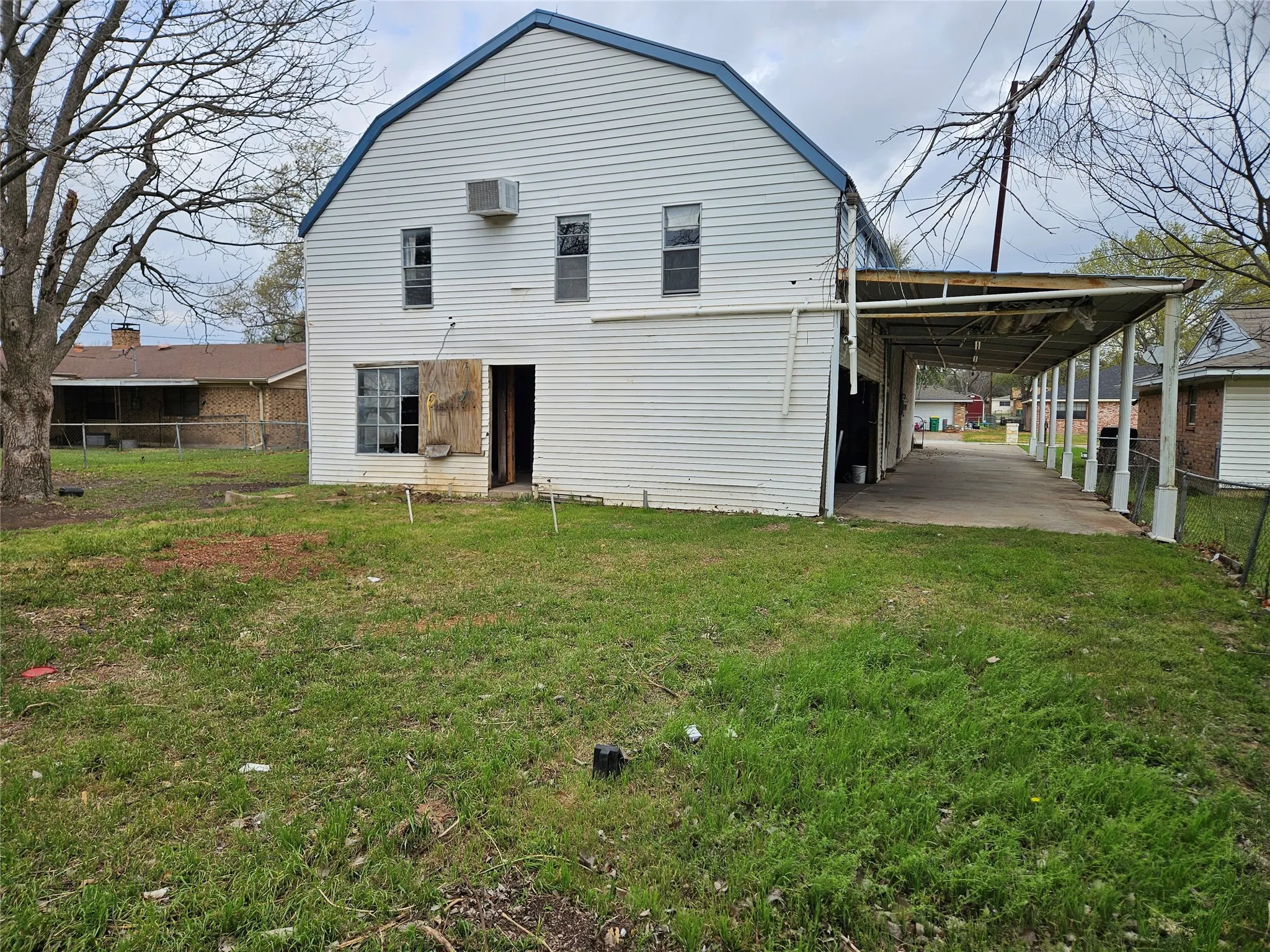 Back of property with a carport and a gambrel roof