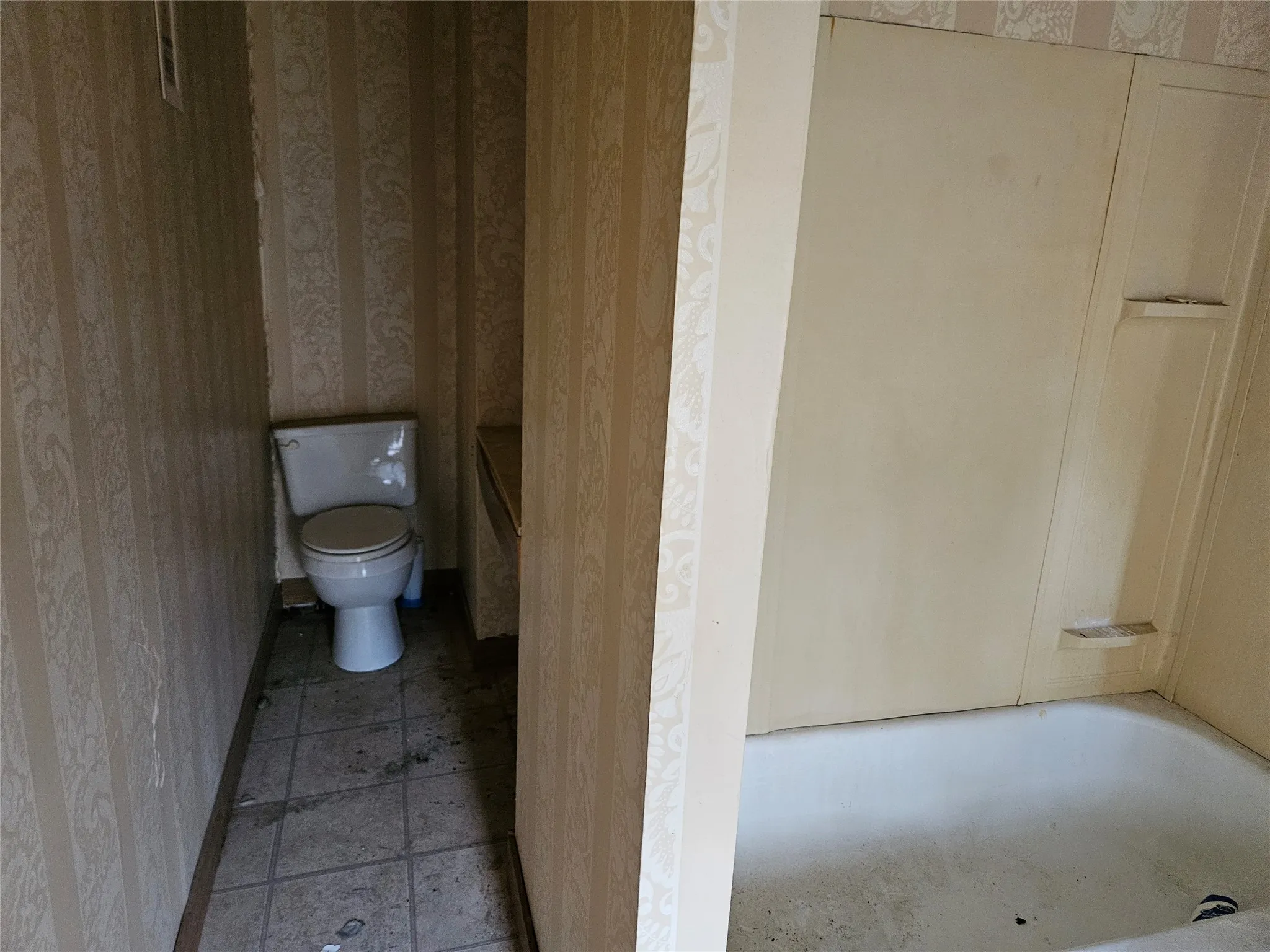 Bathroom with wallpapered walls, a tub to relax in, and light tile patterned floors
