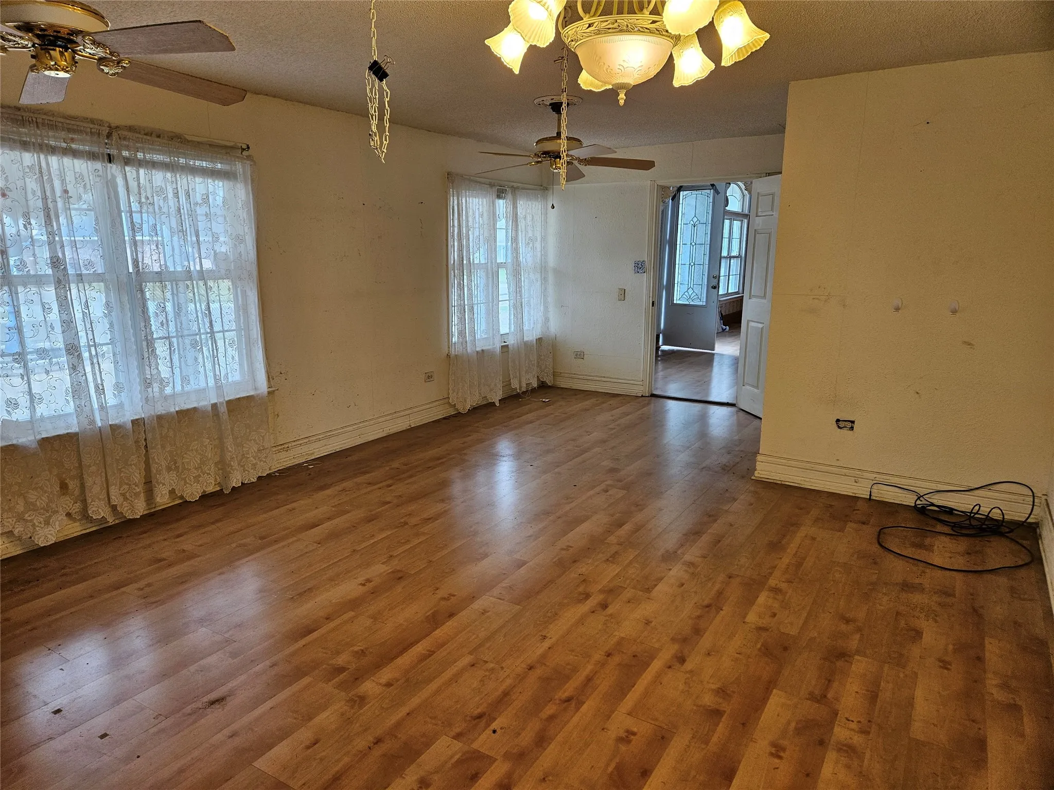 Spare room featuring a ceiling fan, wood finished floors, a textured ceiling, and plenty of natural light