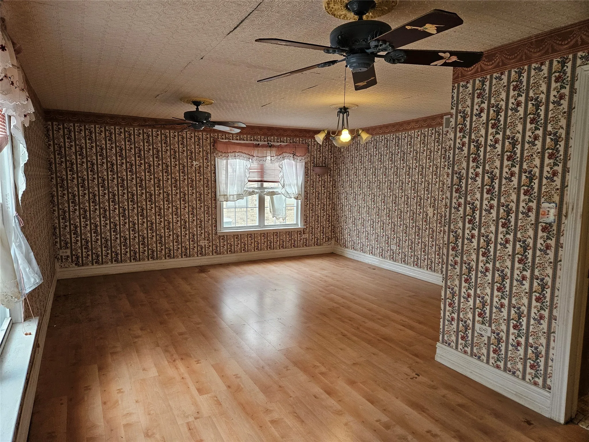 Unfurnished room featuring light wood-style flooring, wallpapered walls, and a ceiling fan