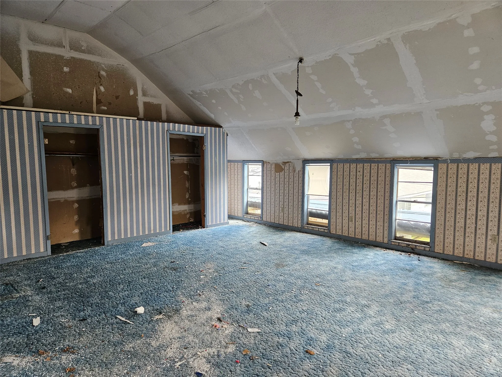 Unfurnished living room with healthy amount of natural light and lofted ceiling
