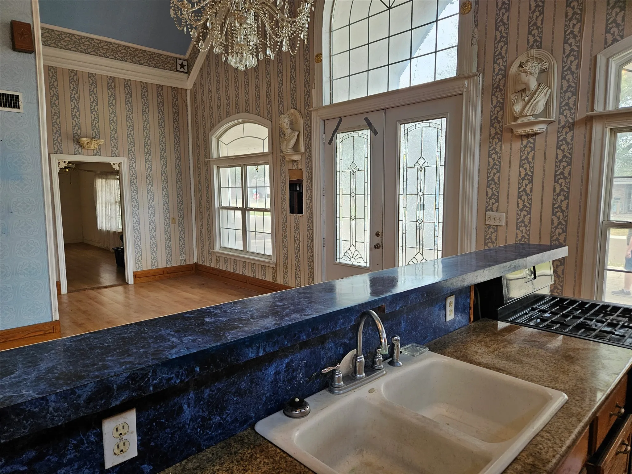 Kitchen featuring wallpapered walls, a chandelier, and wood finished floors