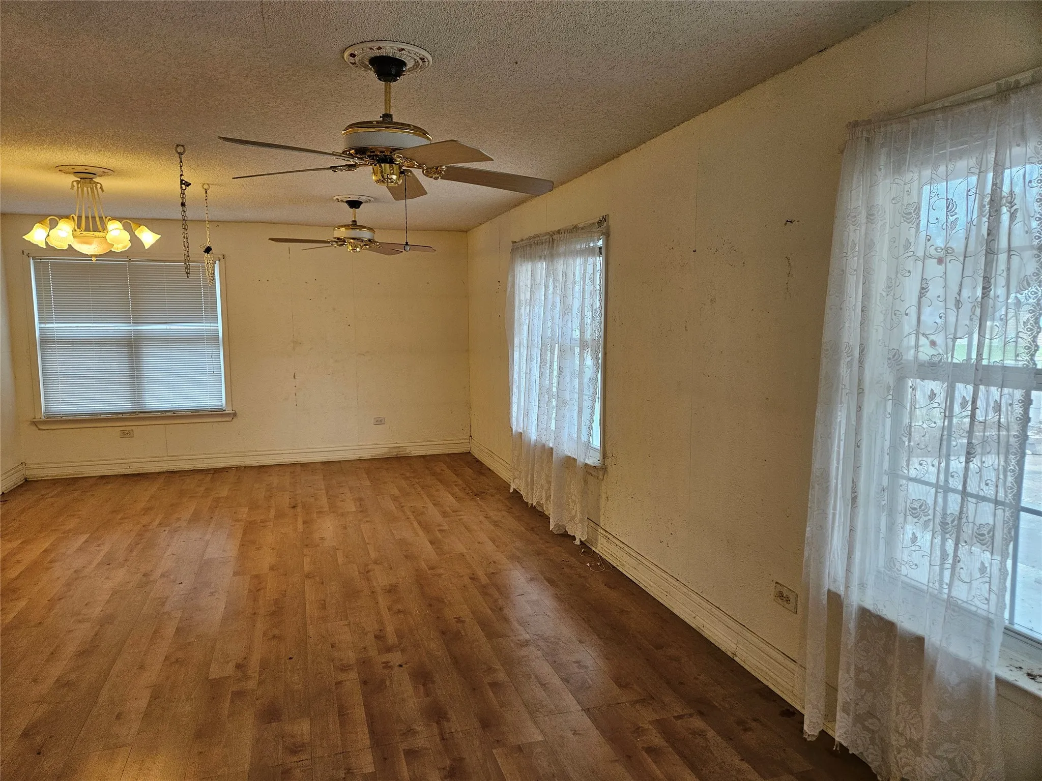 Spare room featuring hardwood / wood-style flooring, a textured ceiling, ceiling fan, and hanging lights