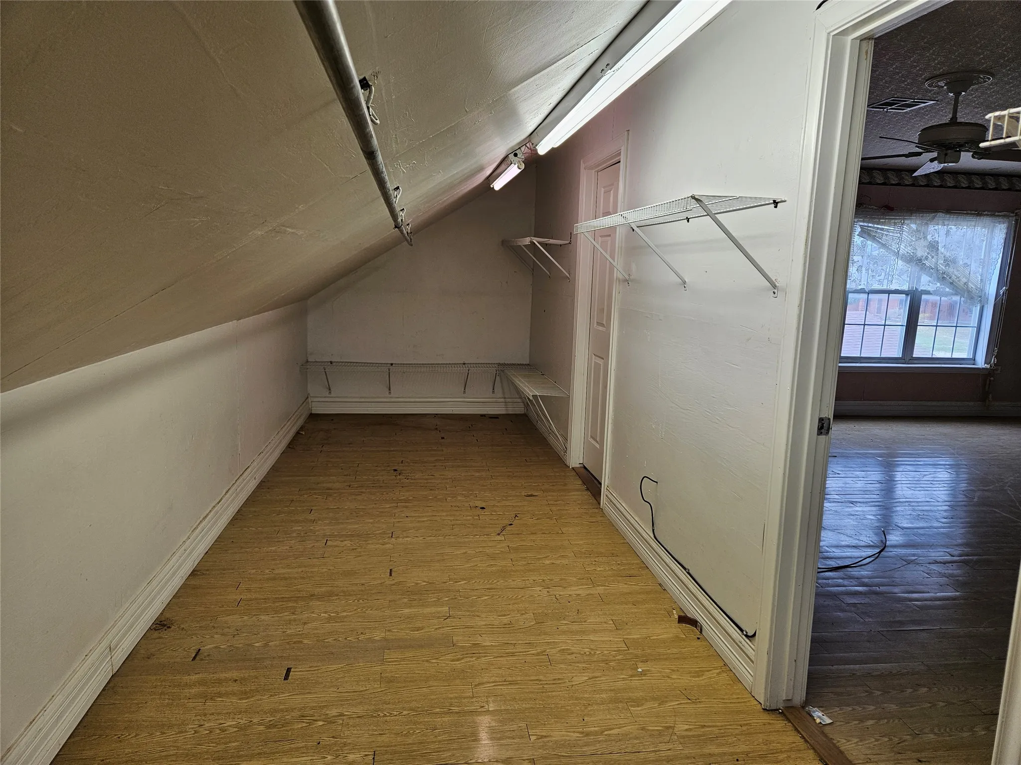 Walk in closet with light wood-type flooring, vaulted ceiling, and a ceiling fan