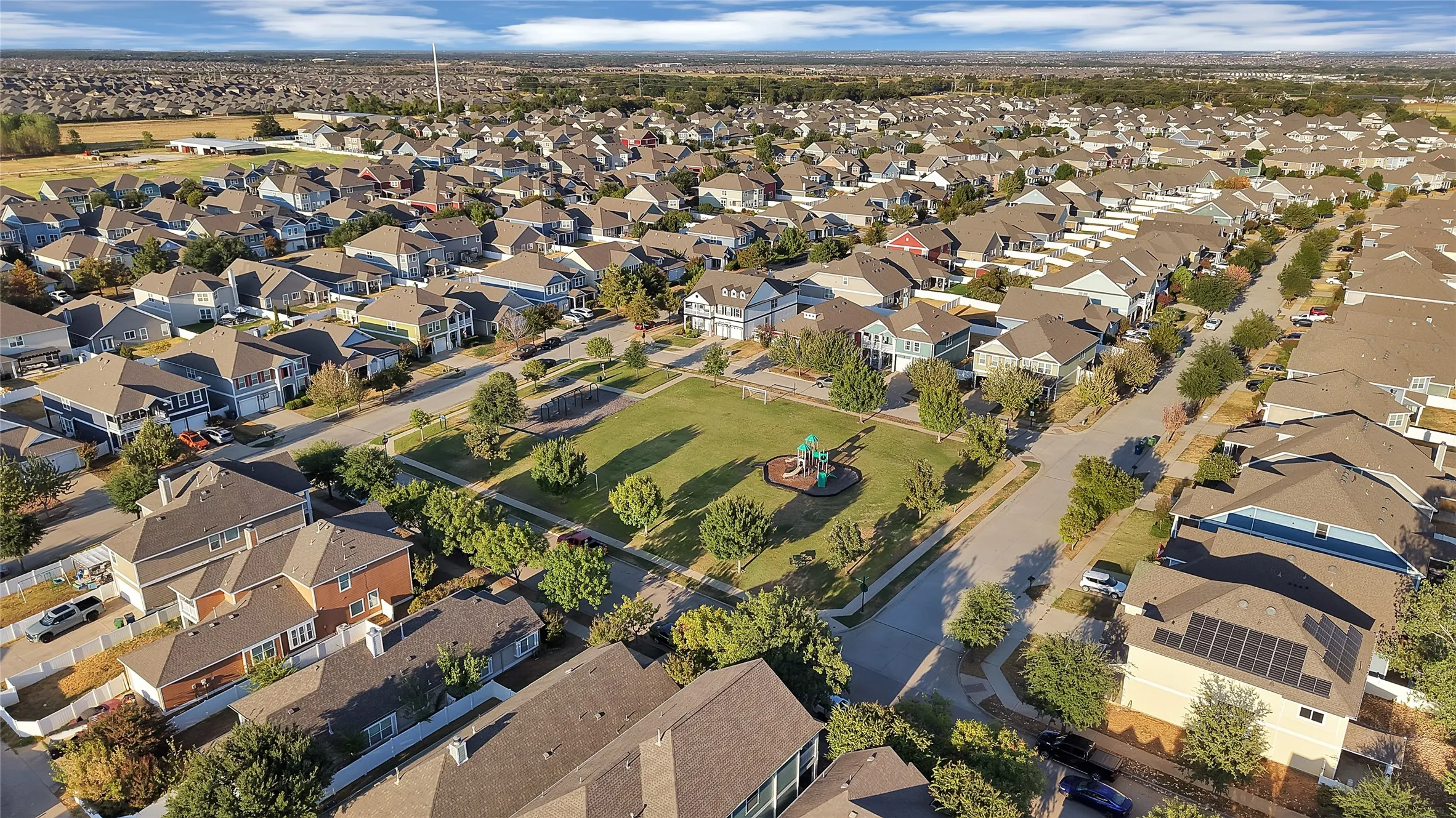 Residential neighborhood with a central green space, mature trees, and a playground