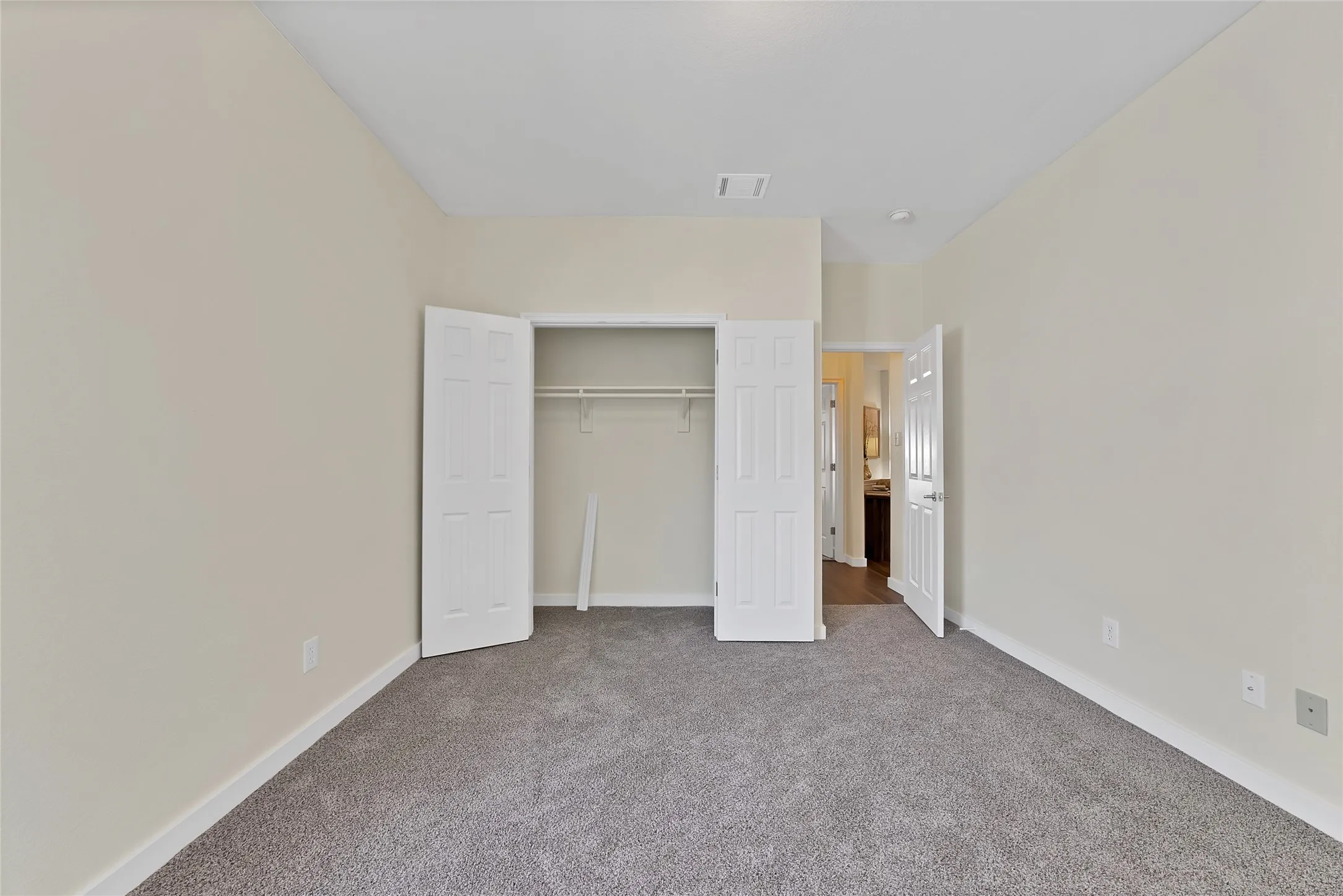Neutral toned walls, gray carpeting, white trim, and a bi-fold closet