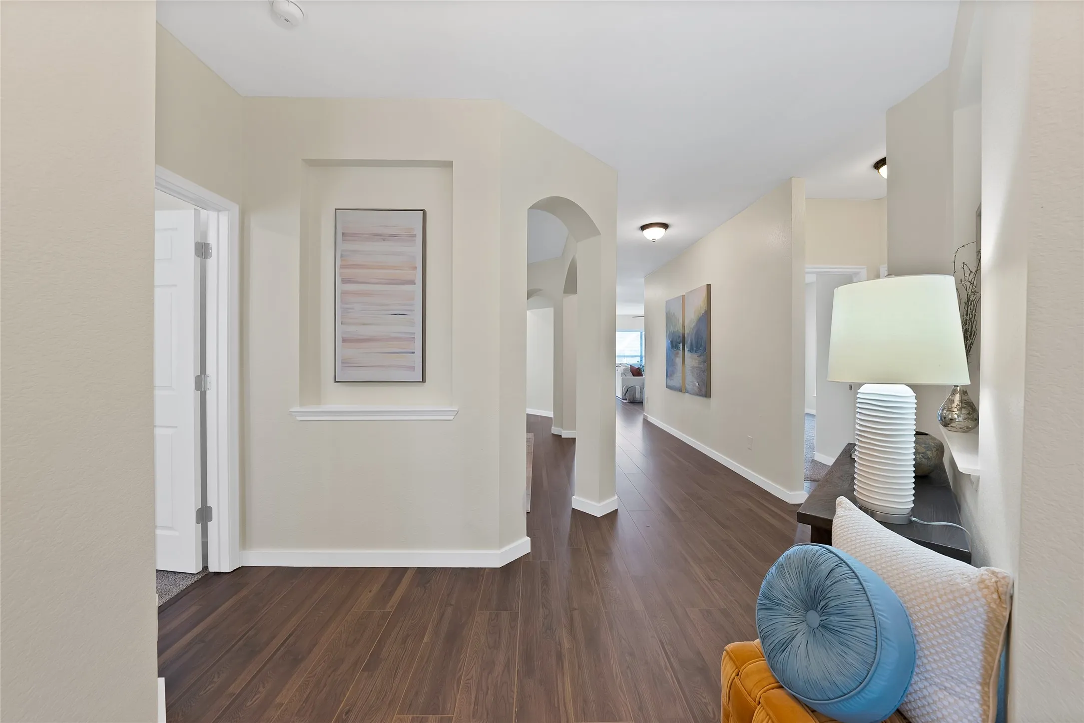 Hallway featuring wood-finish flooring, recessed wall niche, arched doorway, and overhead lighting