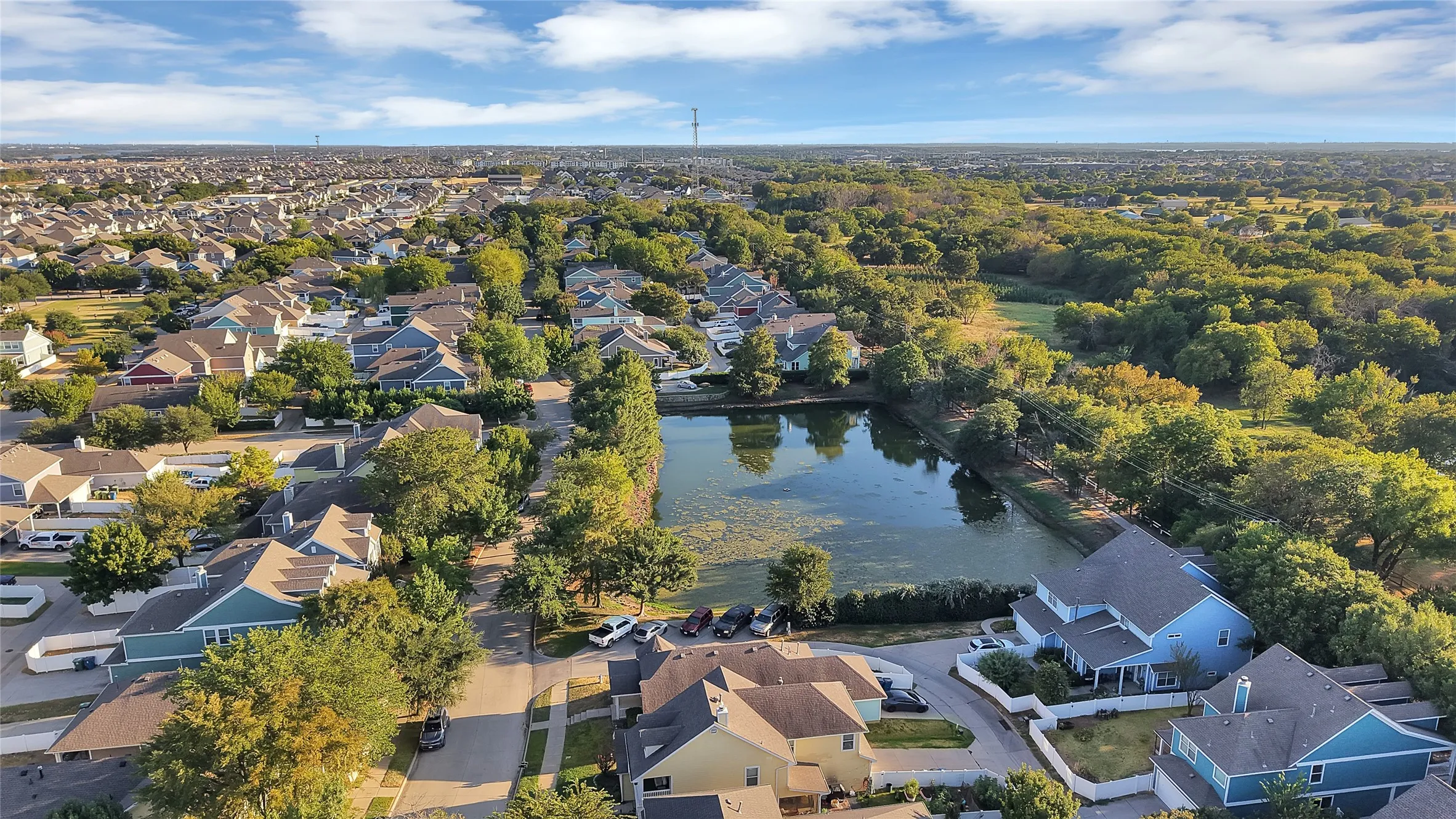 Expansive residential neighborhood featuring numerous properties, mature trees, and a central pond
